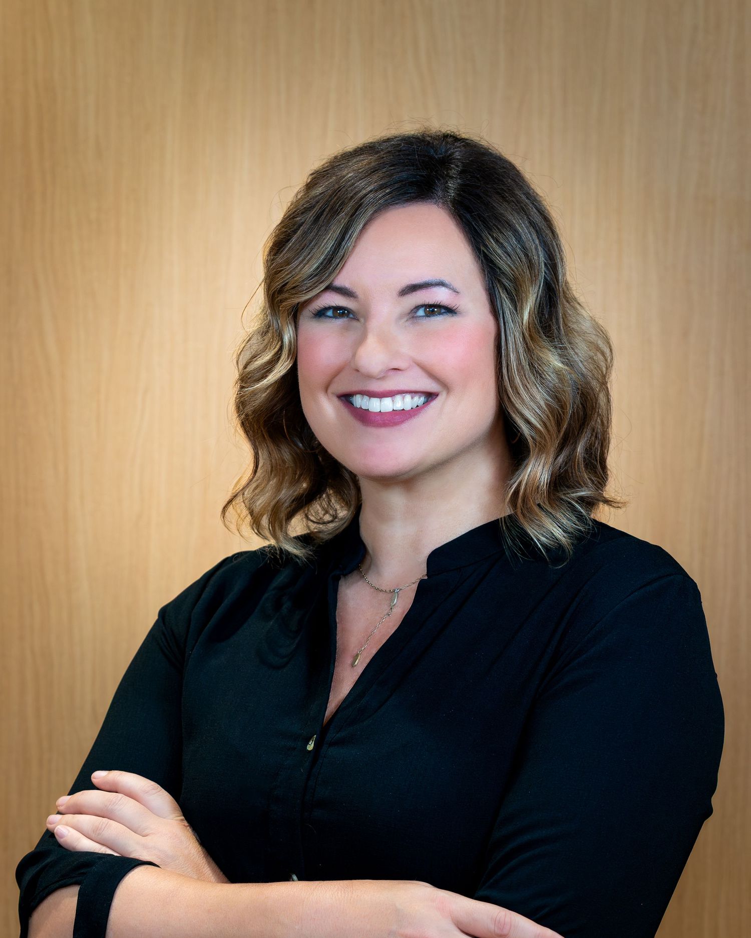 Professional headshot series showing a person in black attire against a warm beige background with varying expressions.