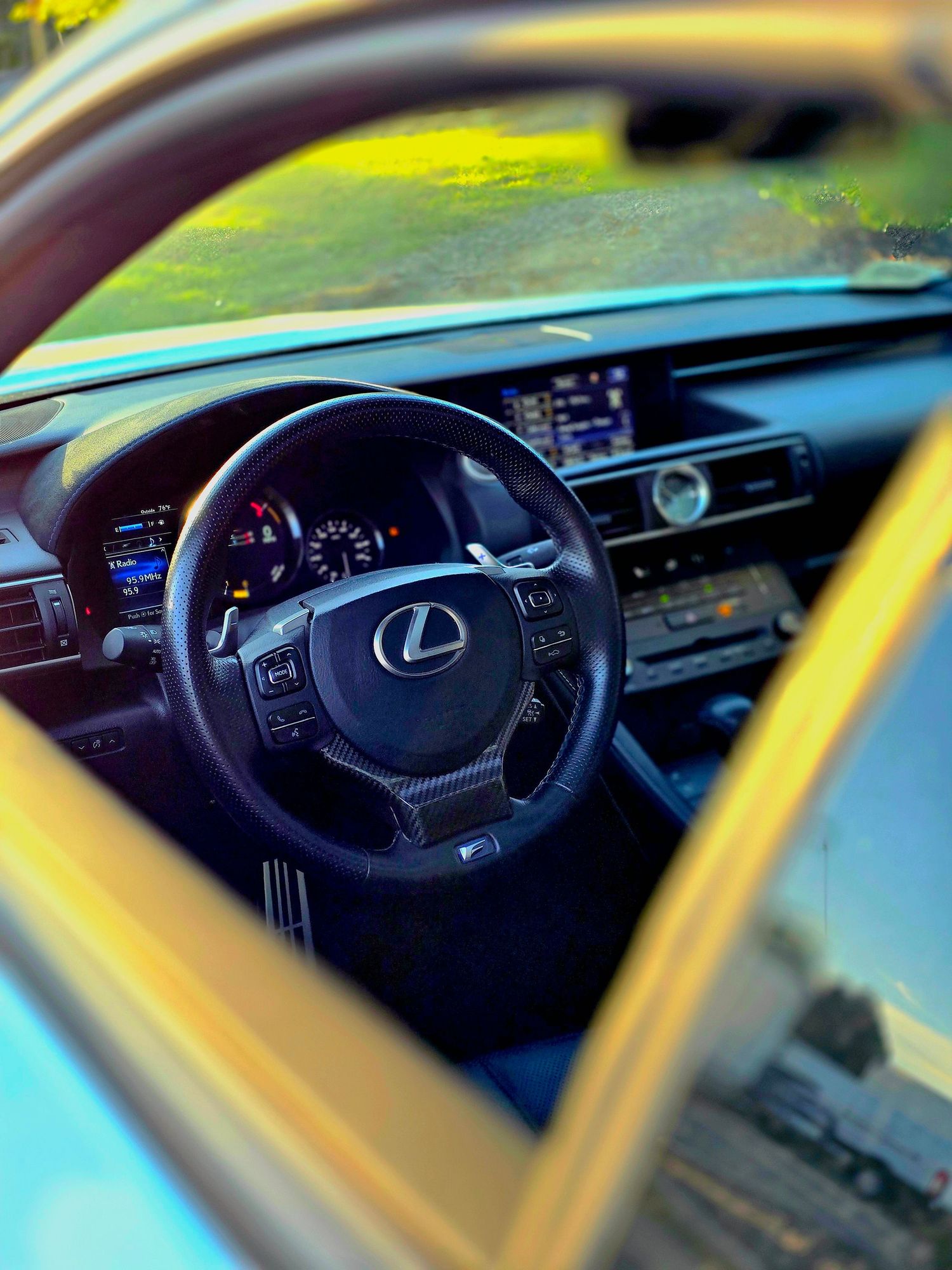 Modern Lexus vehicle interior dashboard and steering wheel with ambient lighting effects.