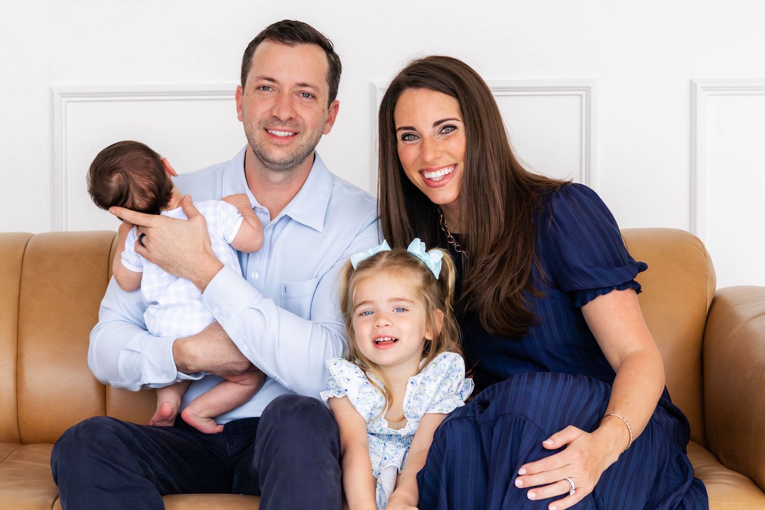 Family of 4 sit together on a couch at a family photo session