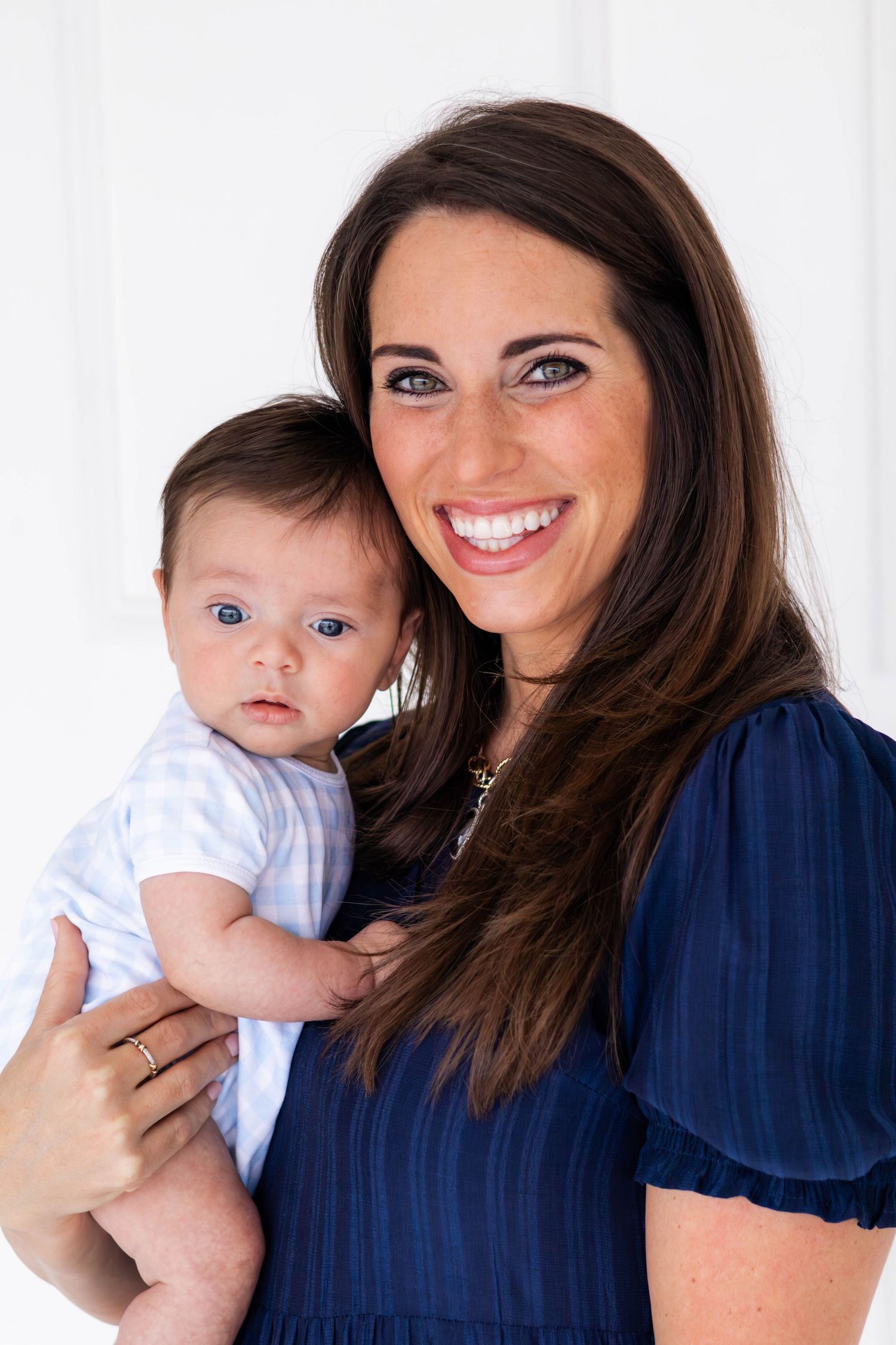 Mom smiling at the camera holding her baby boy