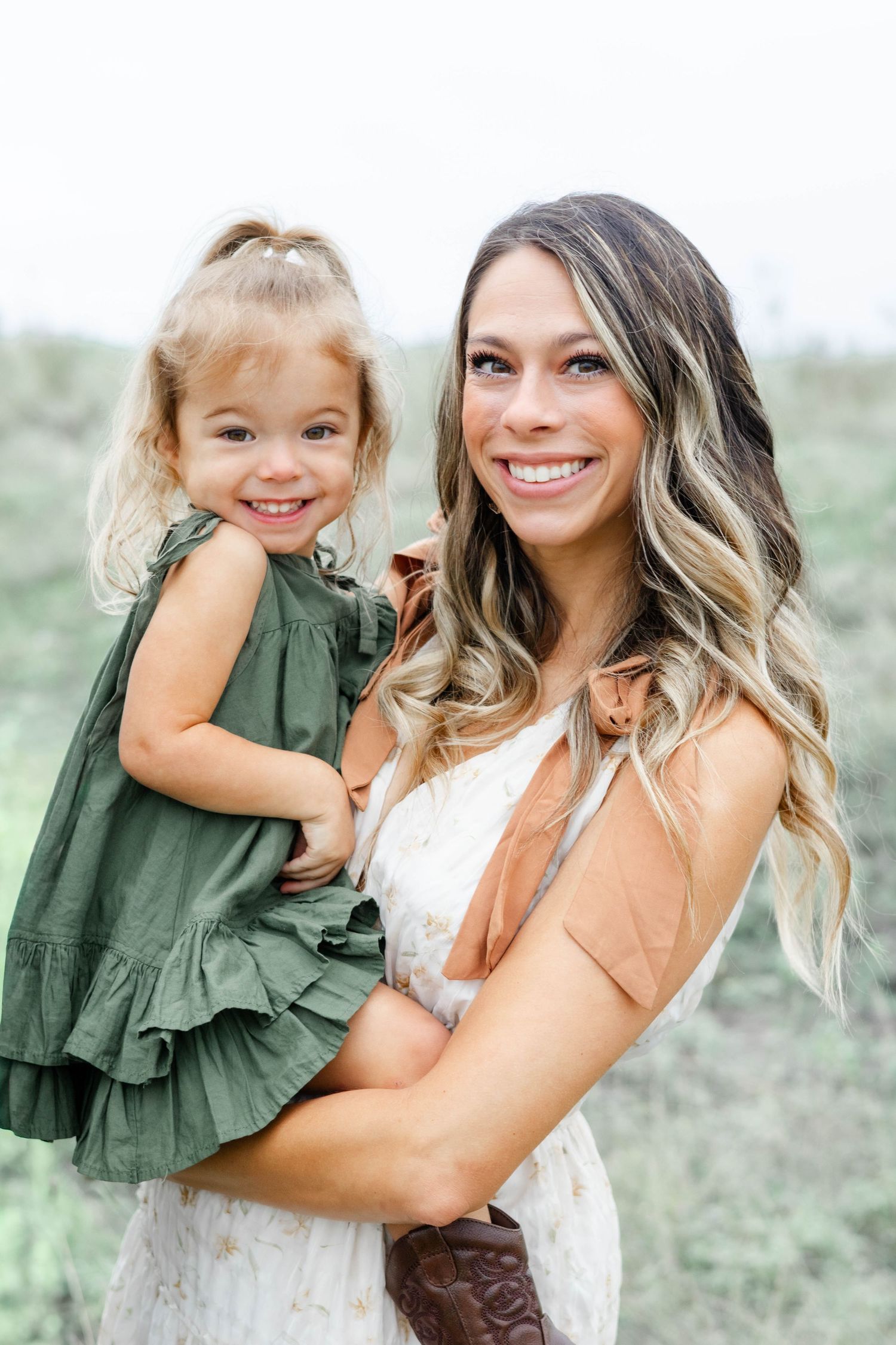 Mom and daughter smile at the camera during family photo session