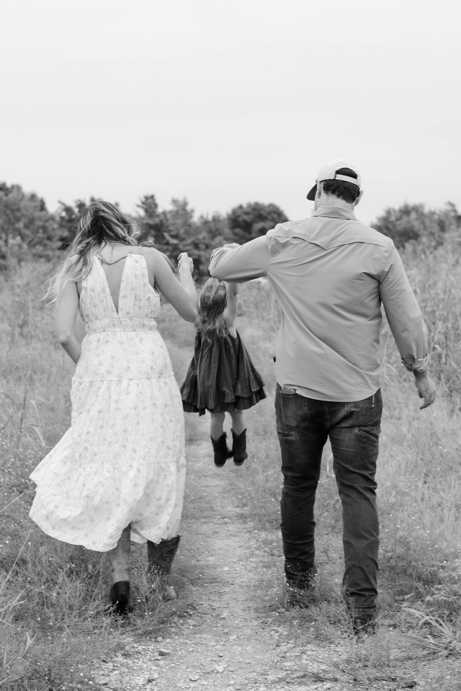 Dallas Parents swing daughter on a path at Arbor Hills Nature Preserve in Plano, Texas