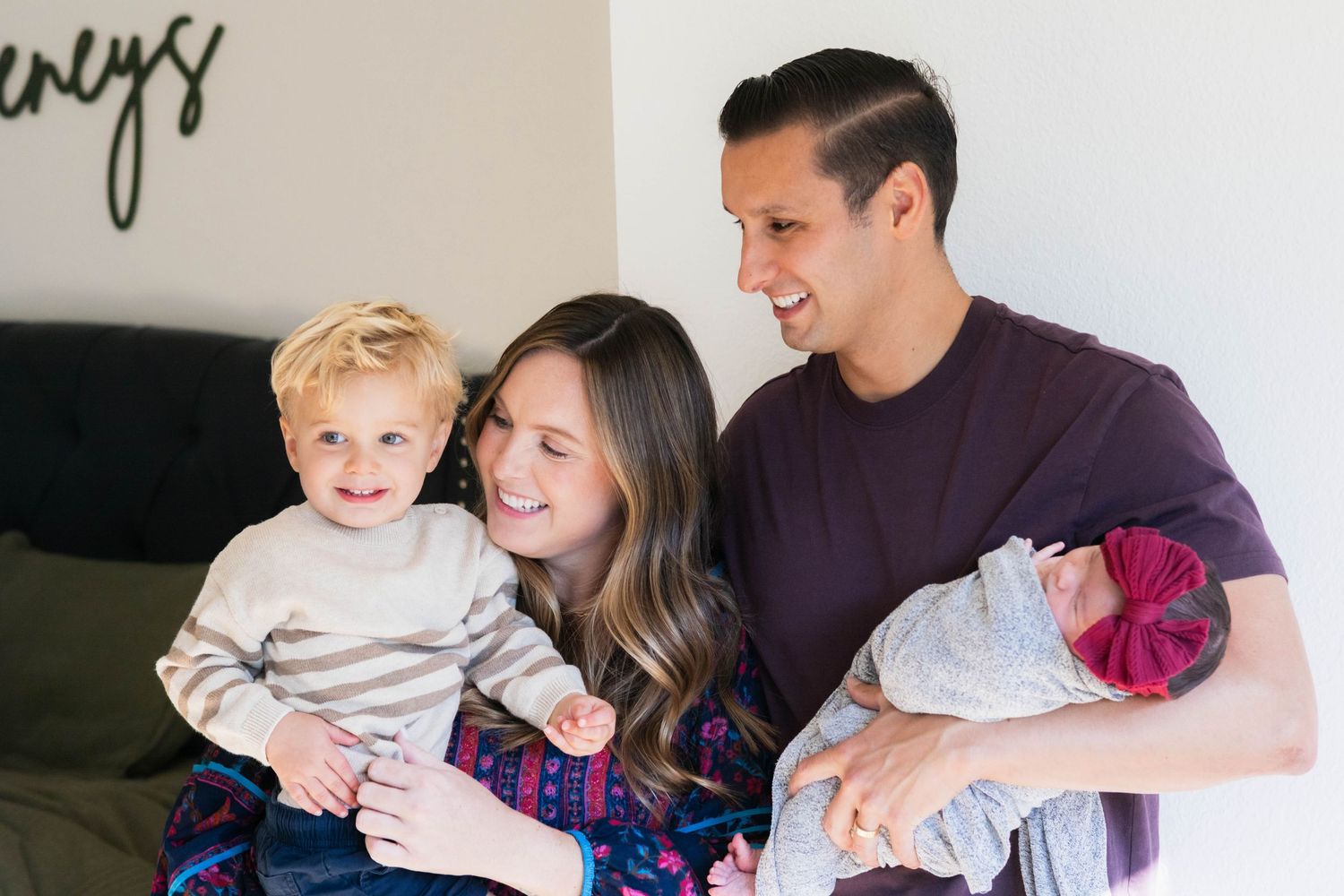 Family of four smile at toddler during DFW newborn photos