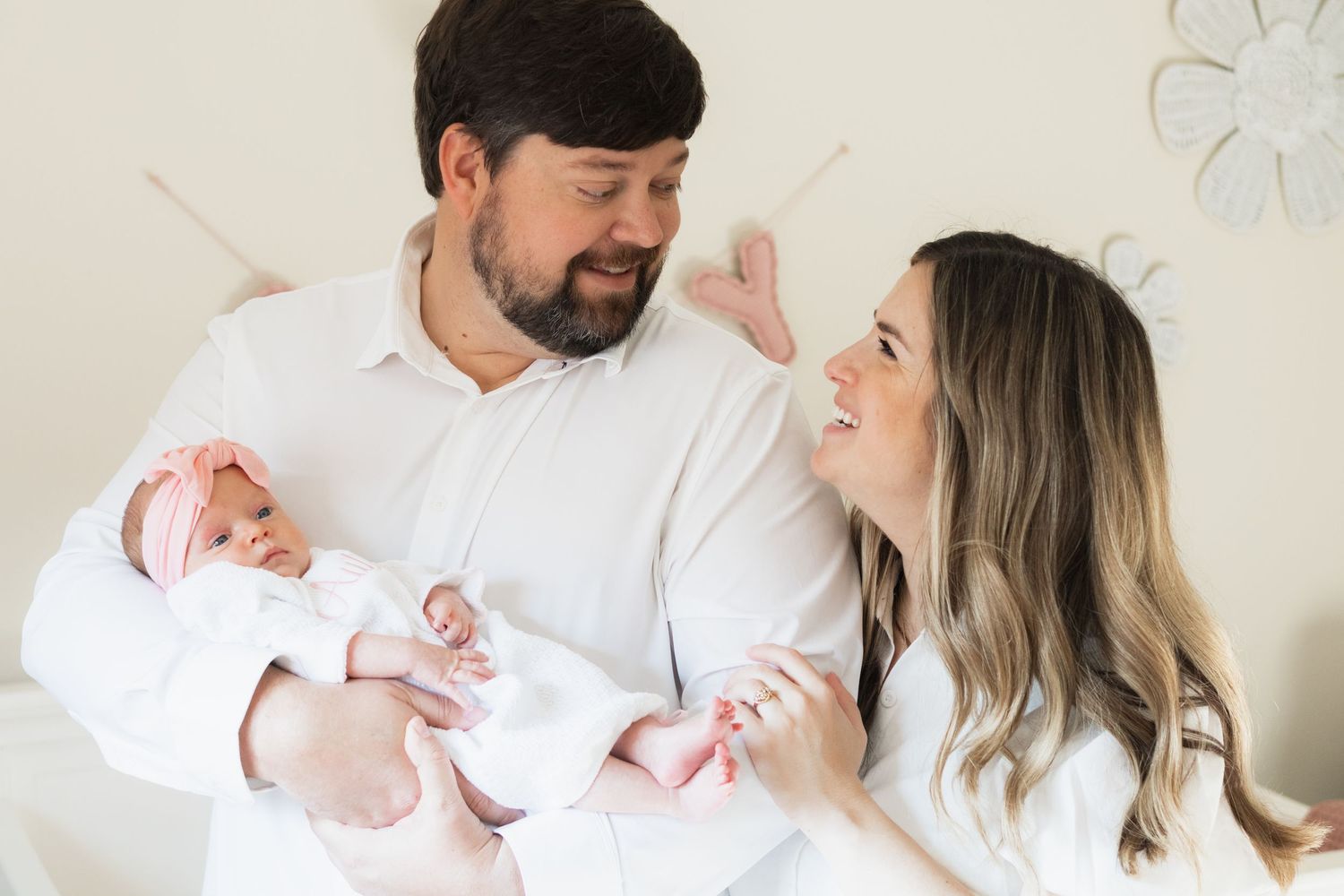 New parents smile at each other while holding newborn baby