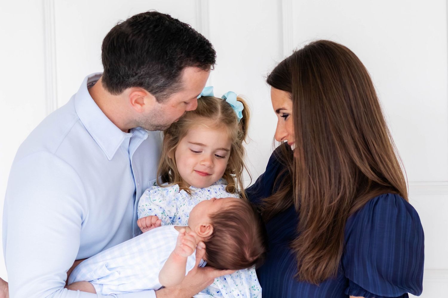 Family of 4 gather and admire new baby boy