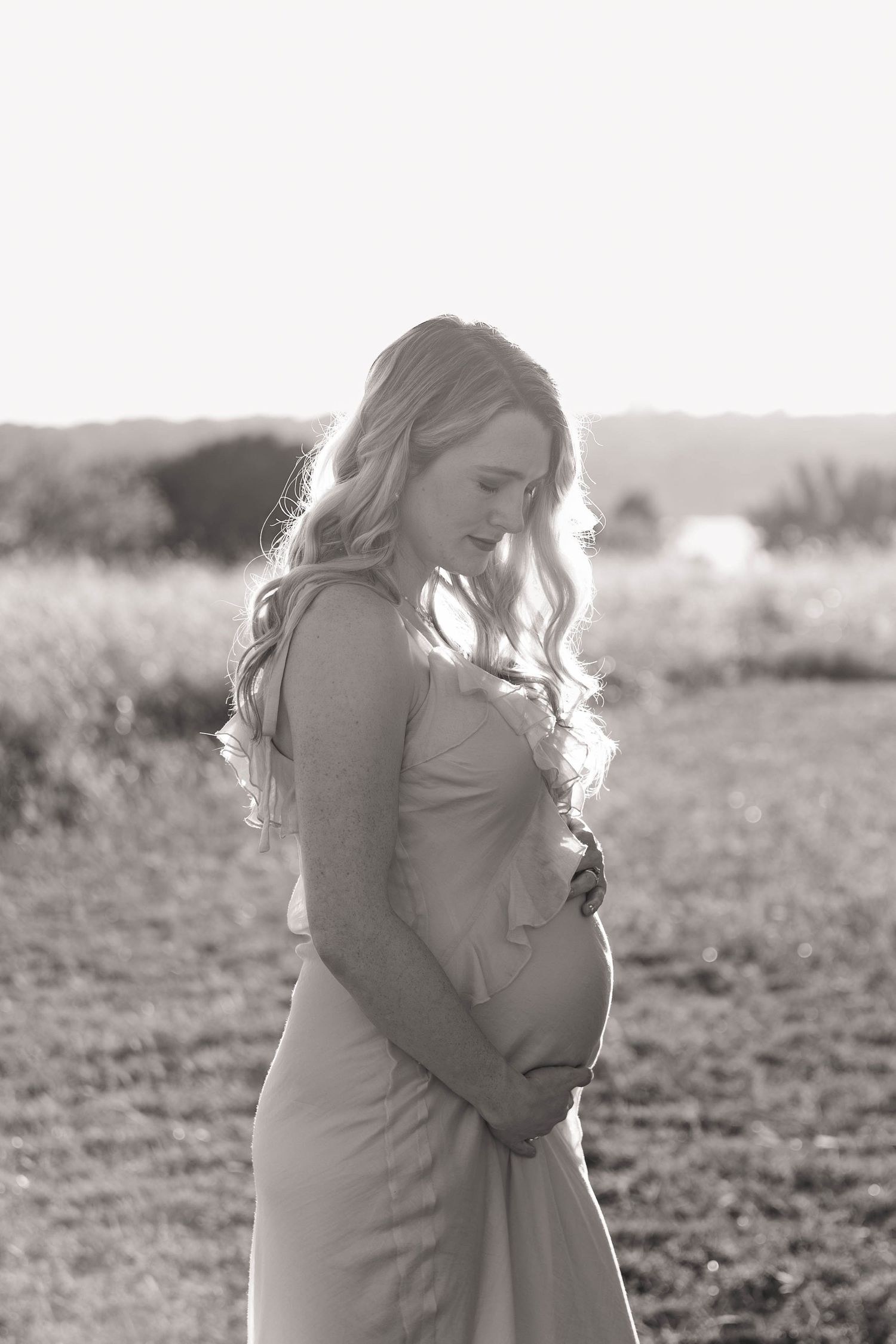 Mom to be holding her belly in a maternity session at White Rock Lake