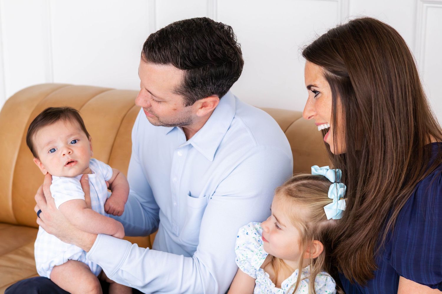 Baby boy stares at camera, as his family looks at him joyously