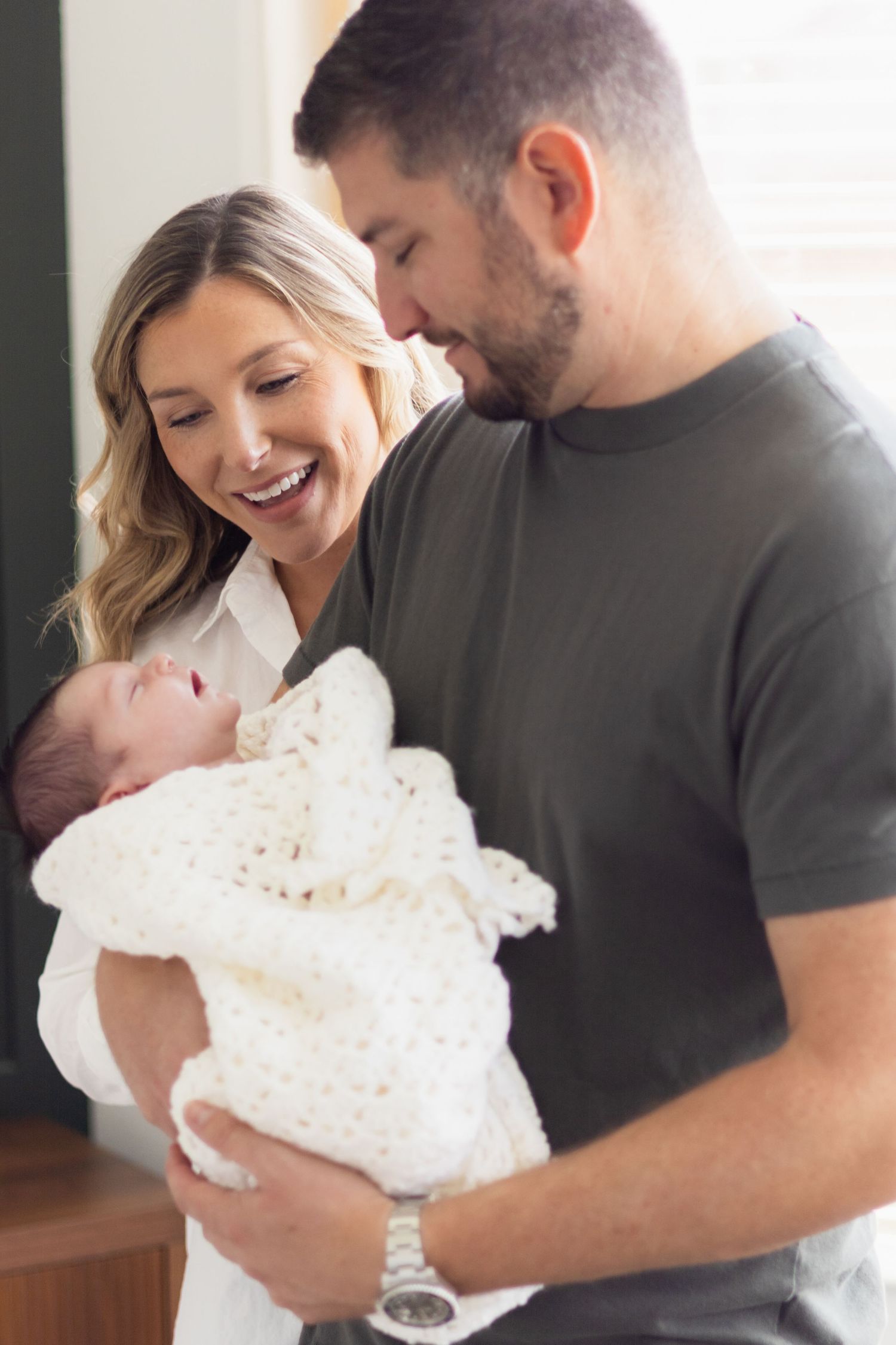 Mom and dad smiling at newborn