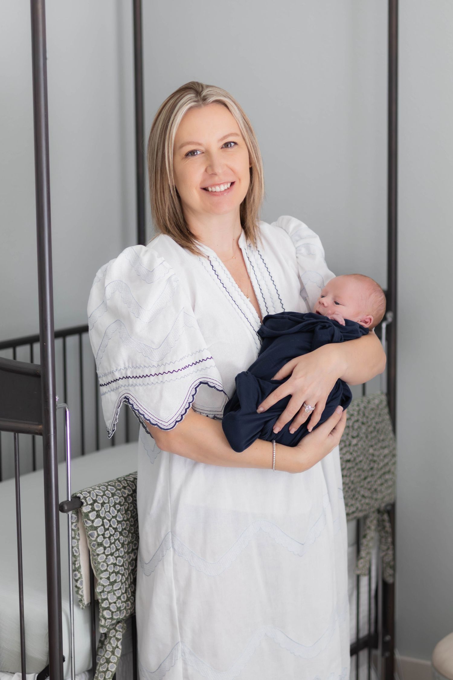 New mom happily rocks baby during DFW newborn photoshoot