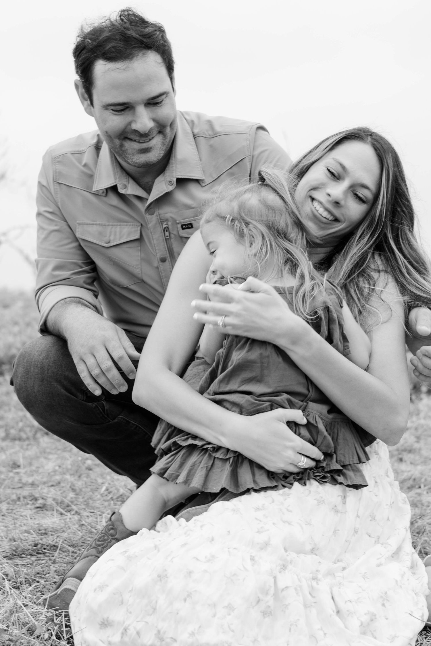 Toddler daughter snuggles close to her mom during family photoshoot