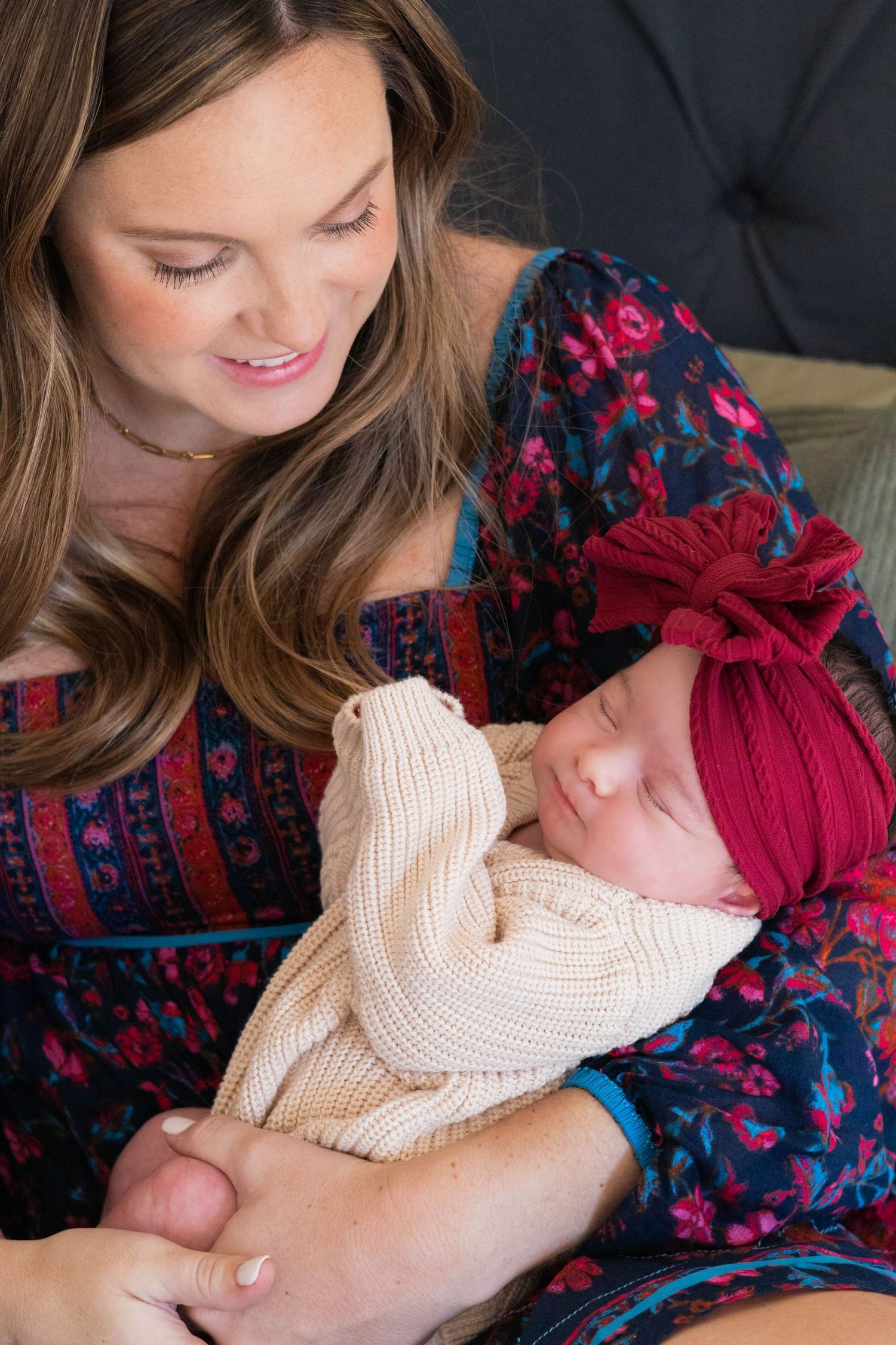 Mom carefully cradles newborn baby girl in red bow