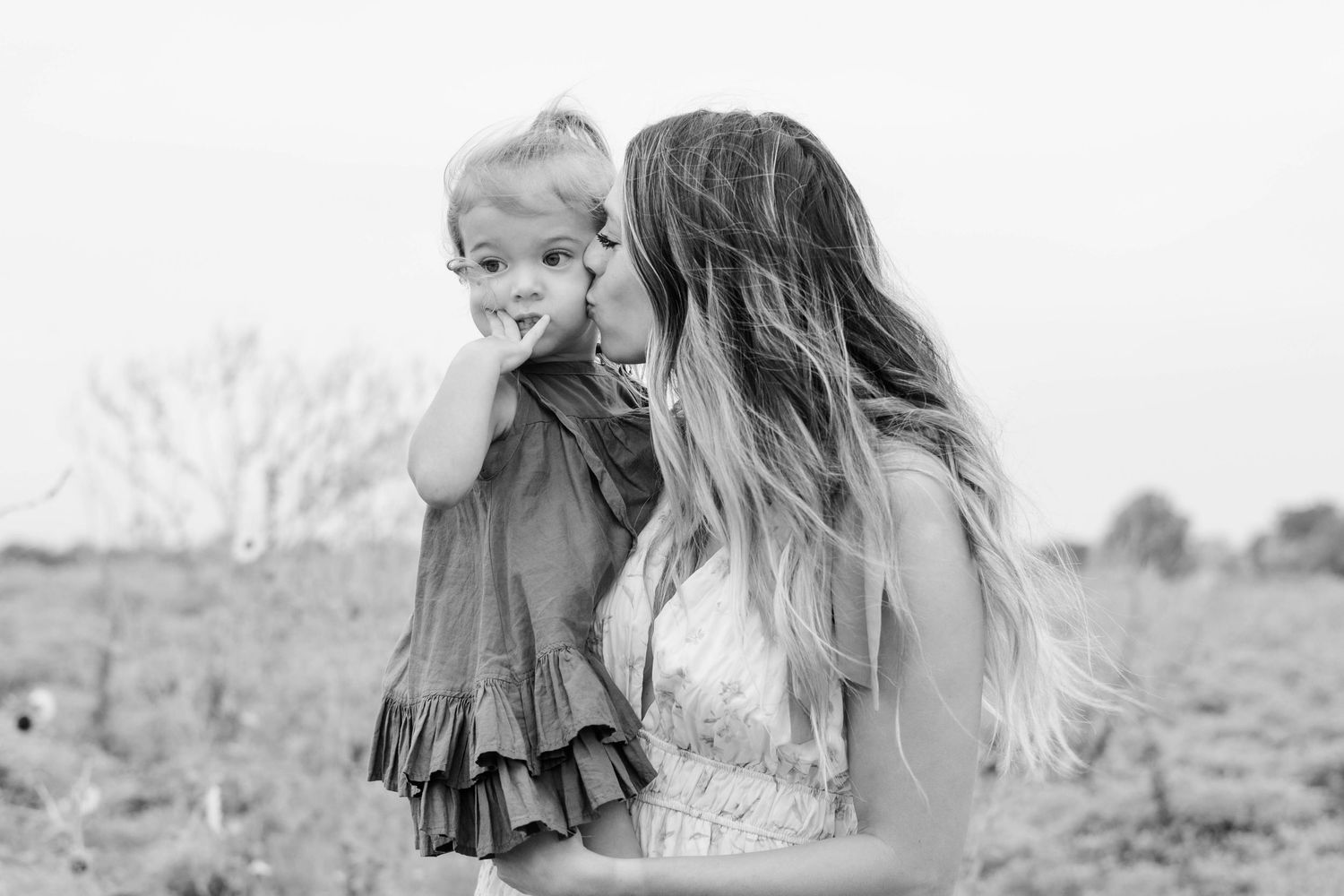 Mom kisses the cheek of her toddler daughter