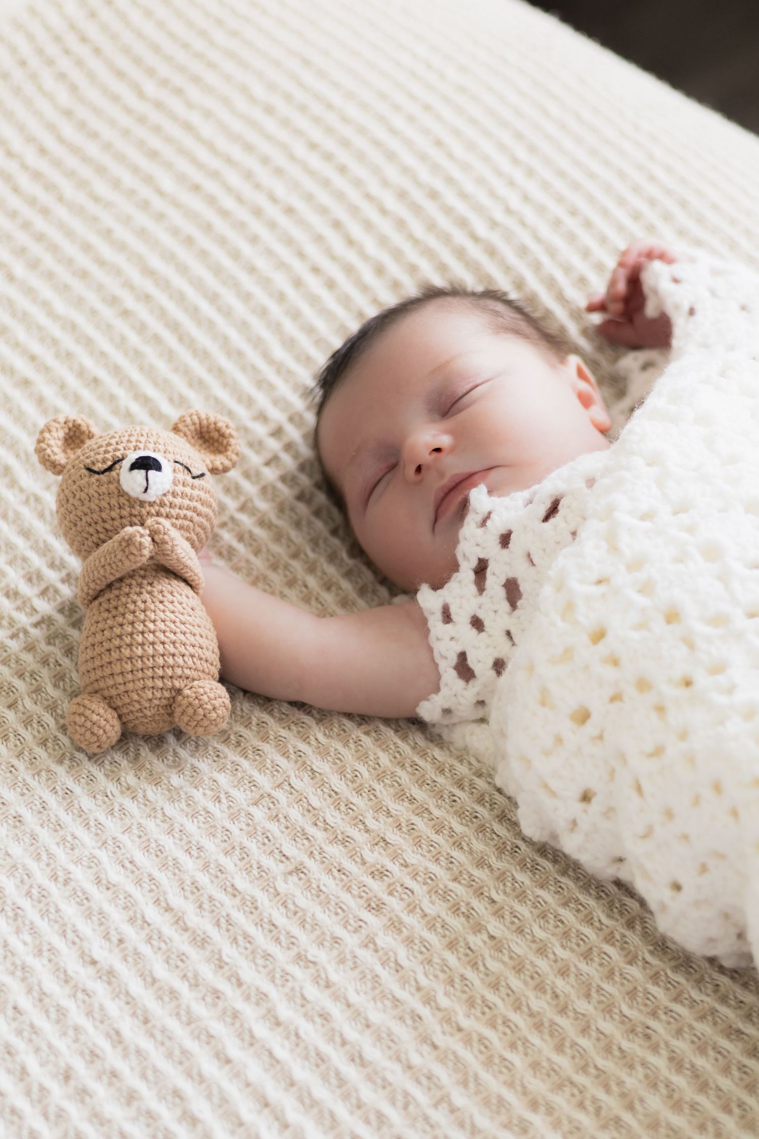 Newborn baby holds stuffed animal in Dallas newborn photography session