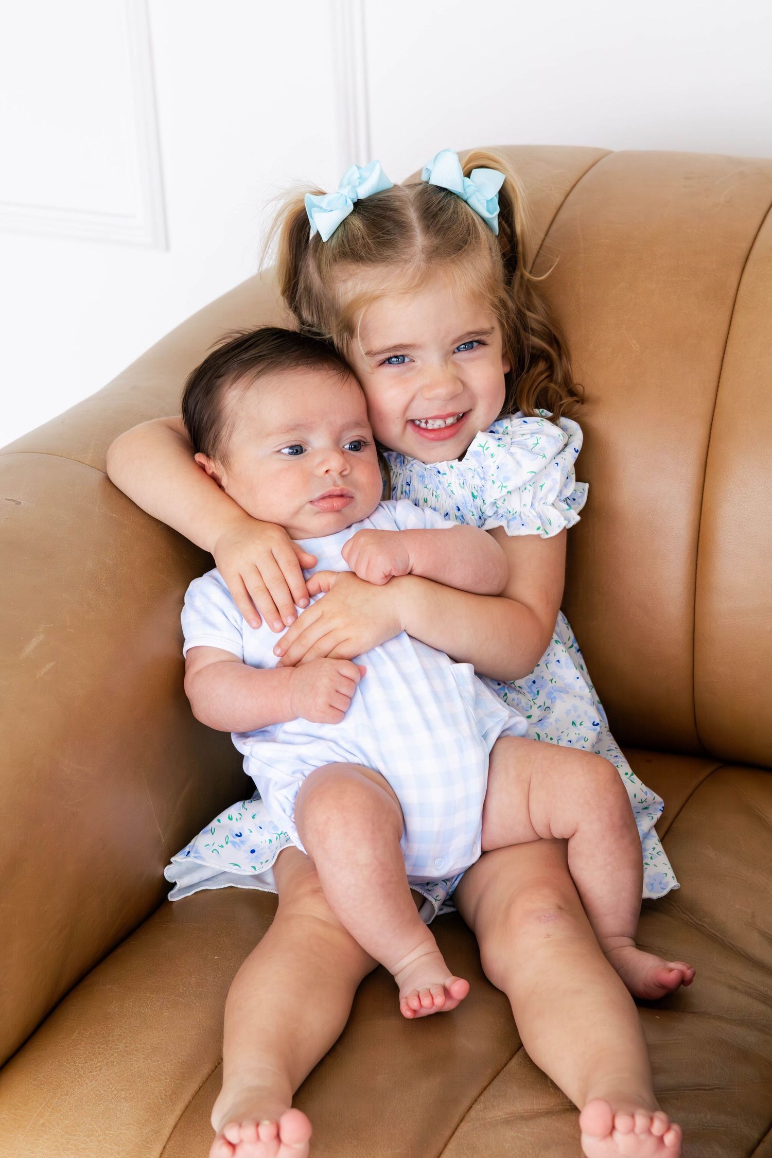 Big sister happily holds new brother on couch