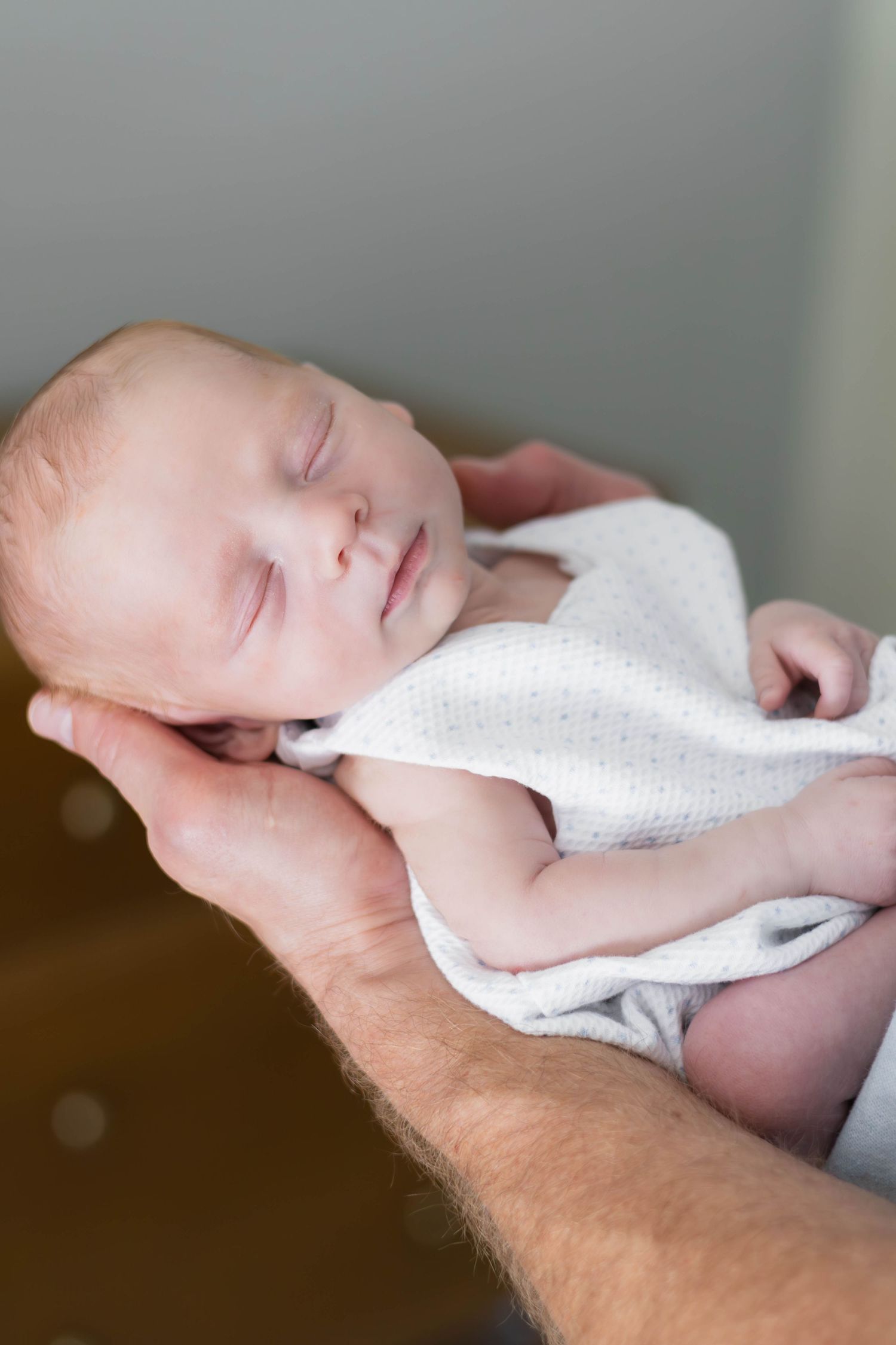 Dad holding out peacefully sleeping baby