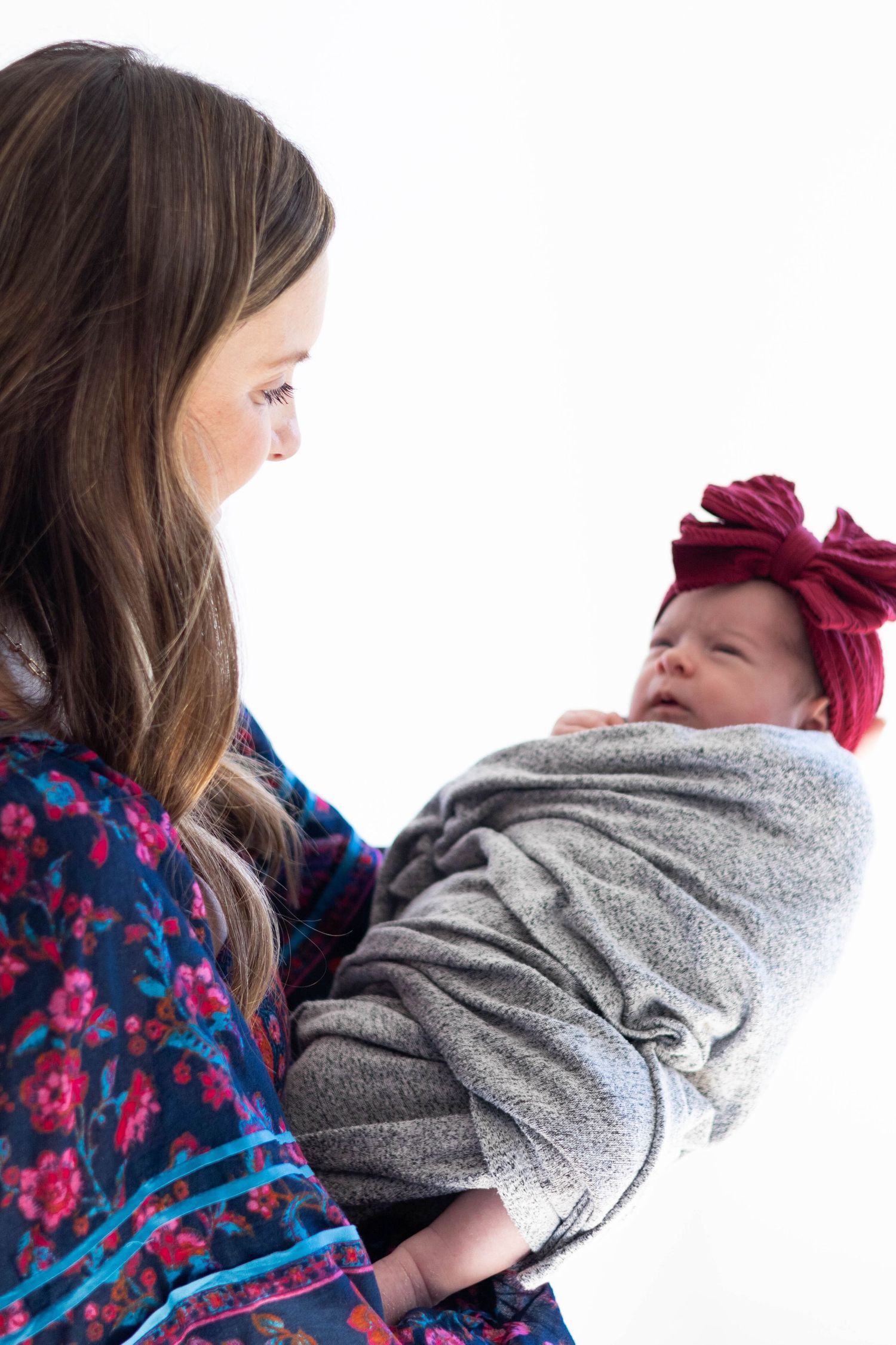 New mom holds out swaddled baby and admires her sweetly