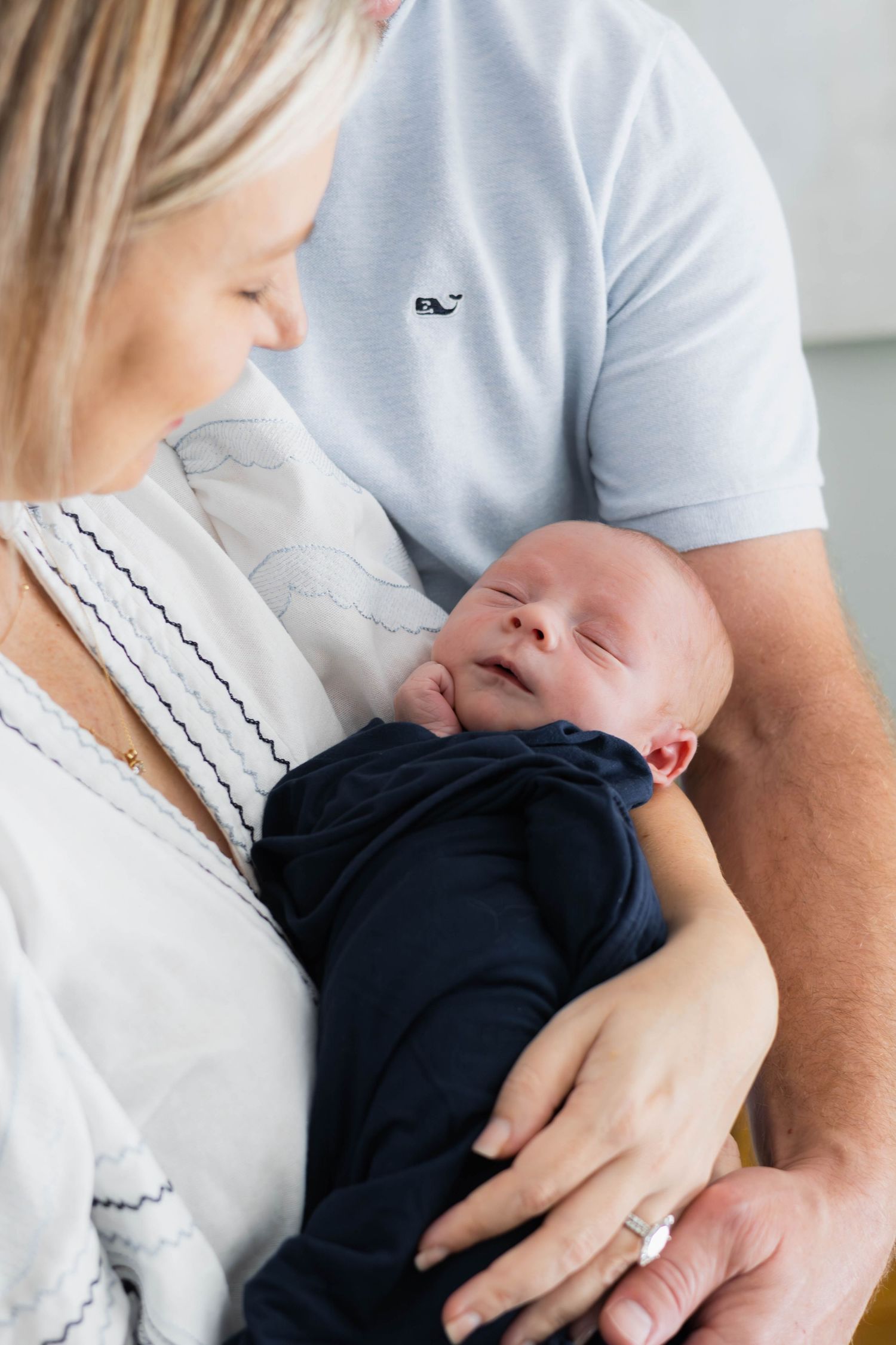 Mom holding newborn with dad's arm wrapped around baby