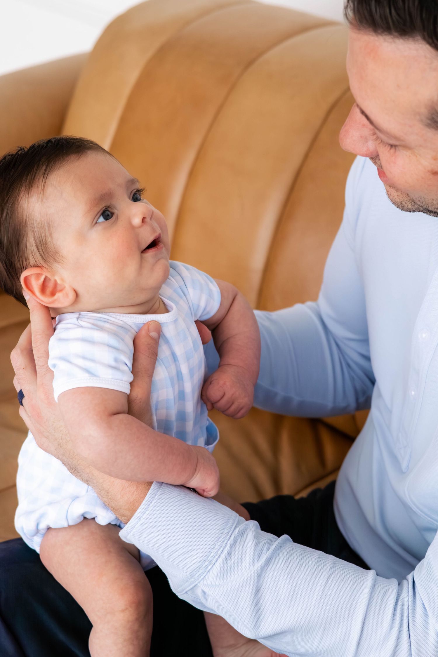 Dad bouncing happy baby on his knee during a Dallas family photo session