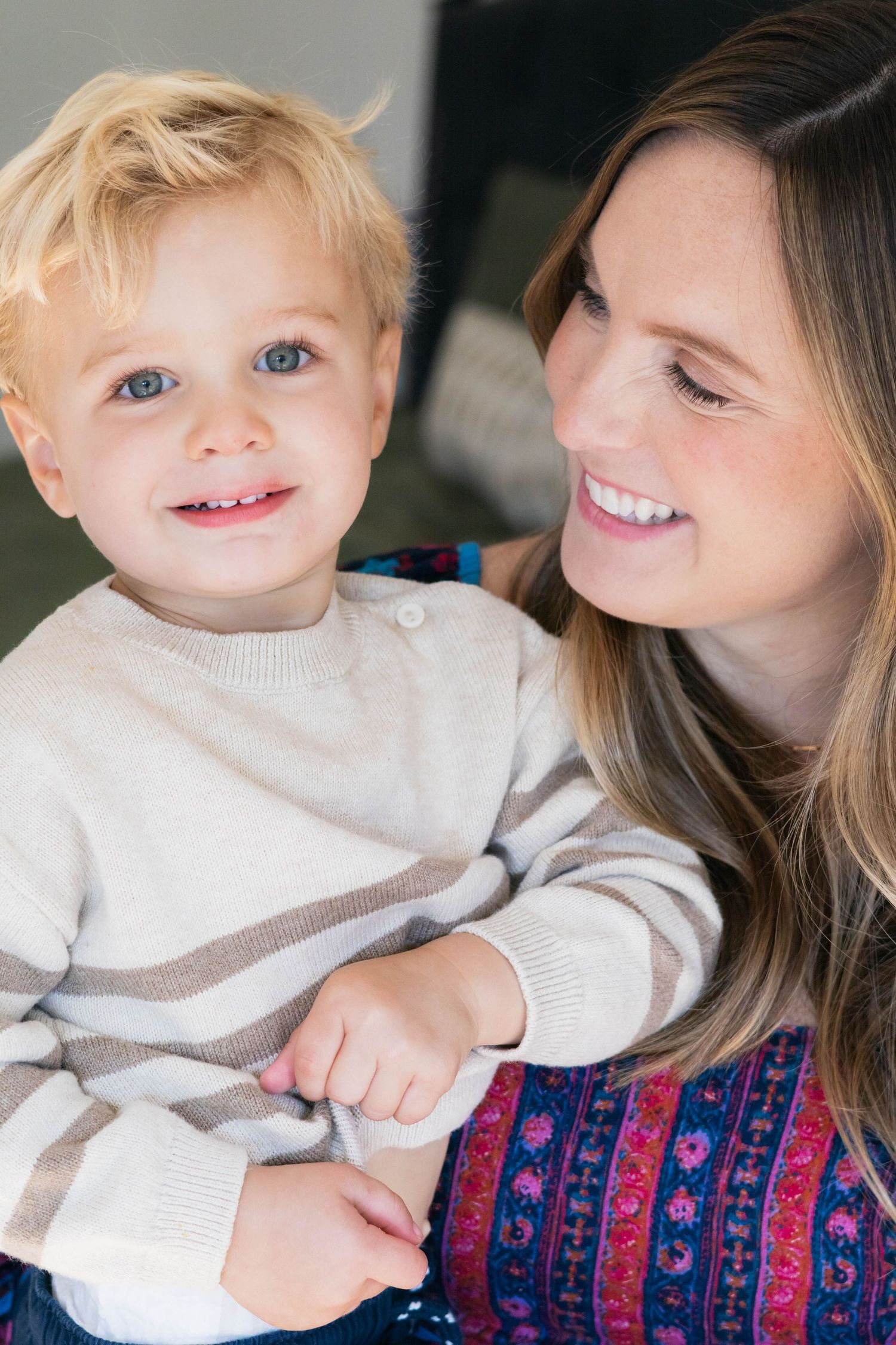 Dallas mom cheerfully holds toddler boy as he smiles at the camera