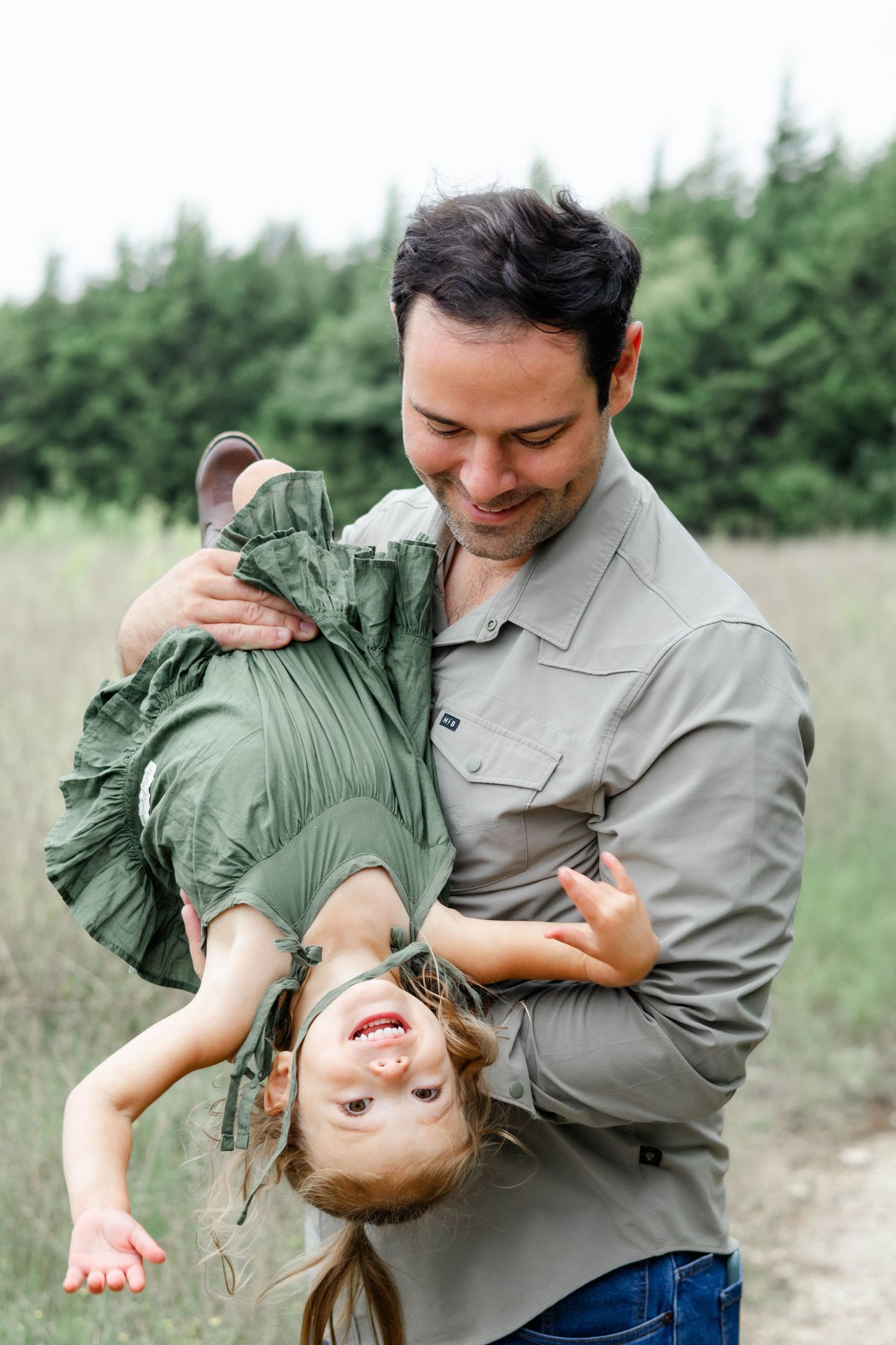 Dad playfully holds daughter upside down