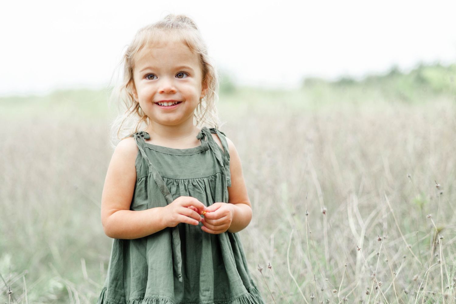 Young girl smiles in a field at Arbor Hills Nature Preserve in Plano, Texas