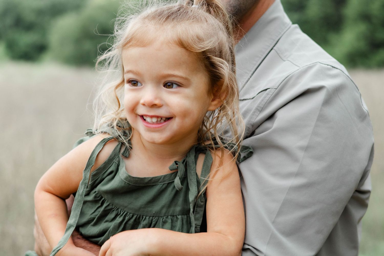 Toddler girl excitedly smiles in dad's arms