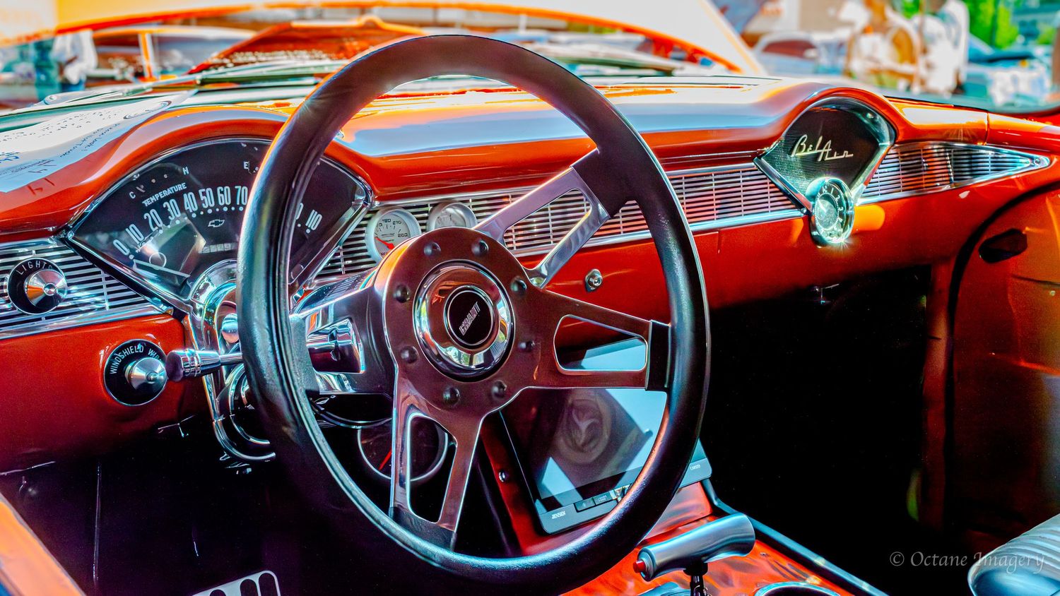 The interior of a custom orange 1955 Chevrolet Bel Air featuring a custom screen and a Hurst RamRod shifter.