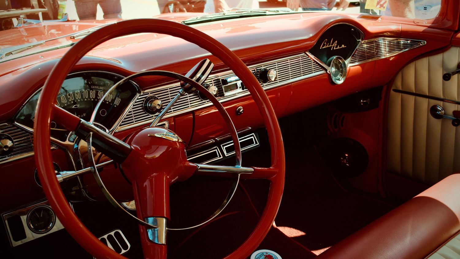 The interior of a red and white 1956 Chevrolet Bel Air featuring an original steering wheel and custom red and white leather seats.