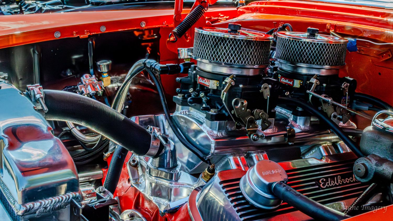 A side view of an orange 396 cubic inch Chevrolet engine with dual carburetors inside an orange engine bay.