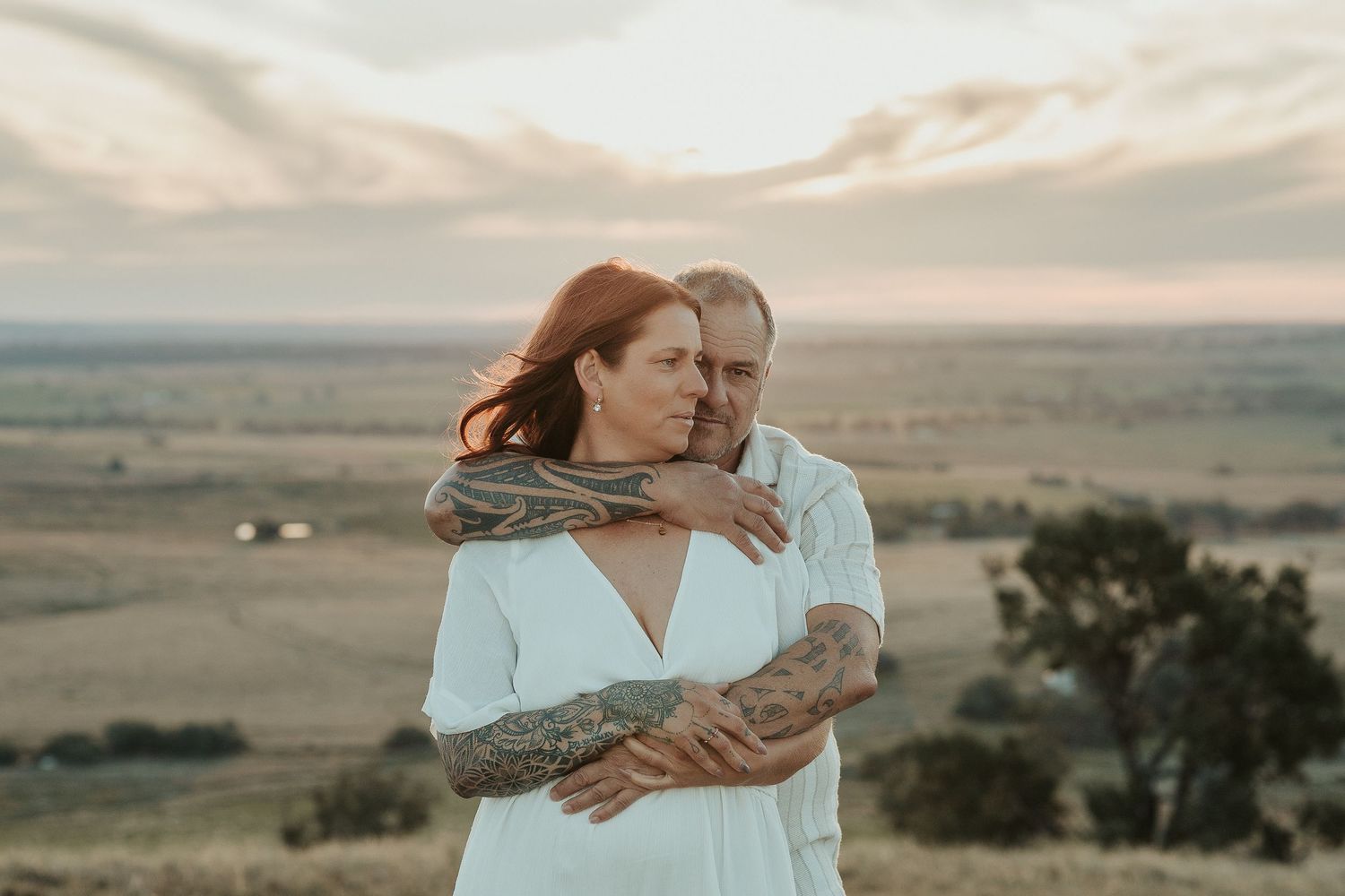 A tender moment between two people against a scenic desert backdrop at sunset.