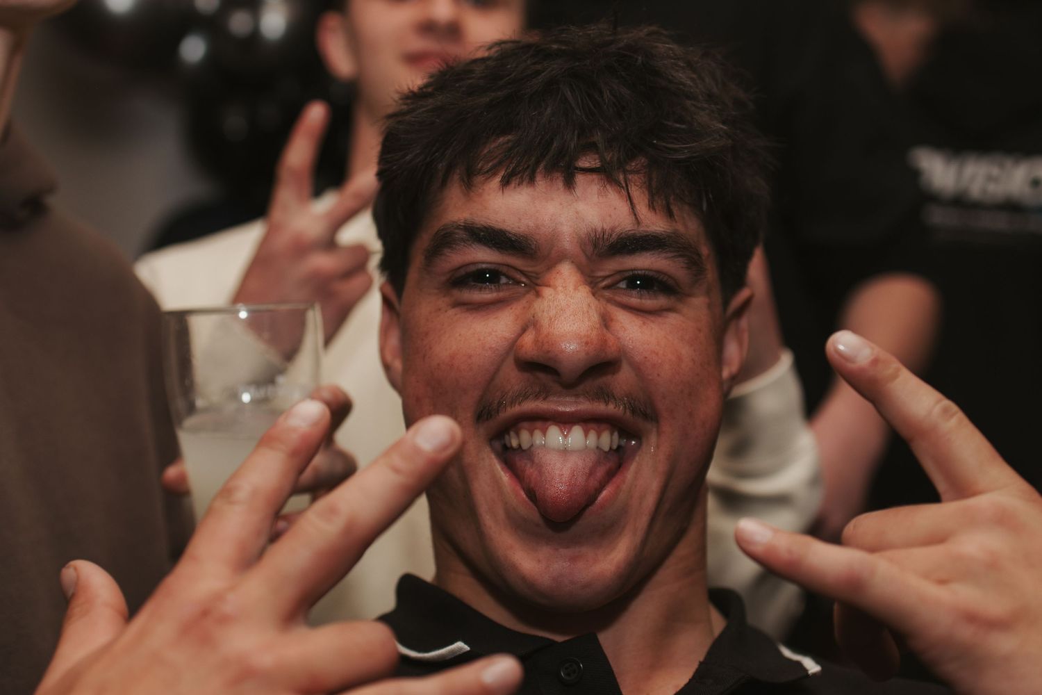 Person making playful expression at party with dark background.