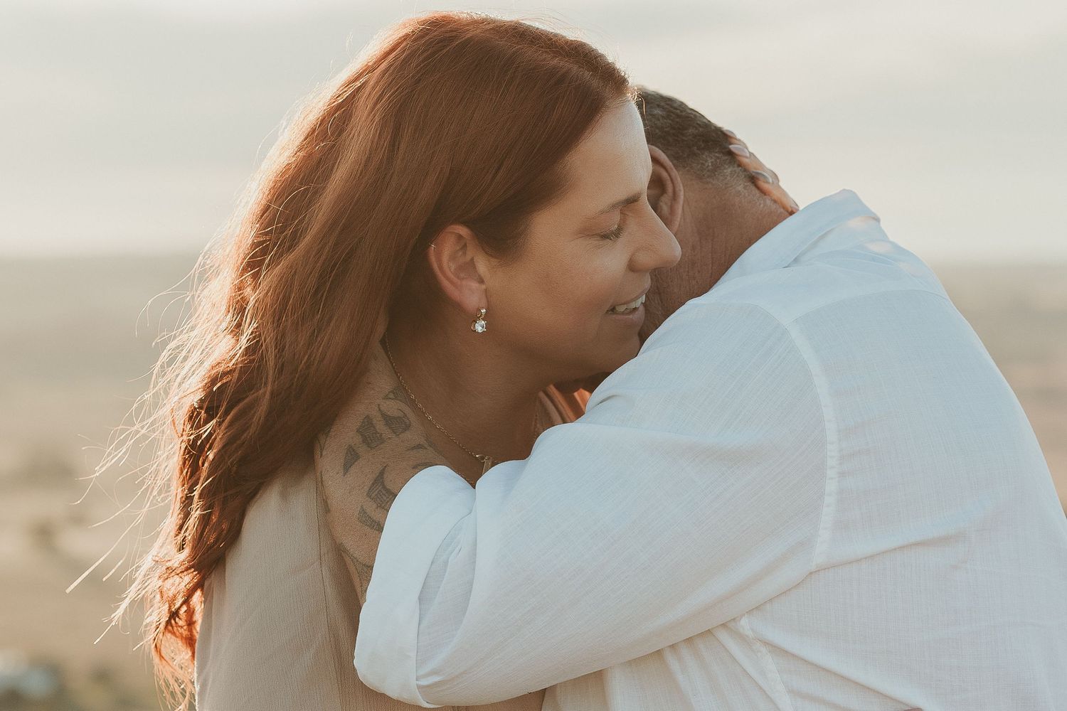 Intimate embrace captured during sunset photoshoot on hilltop.