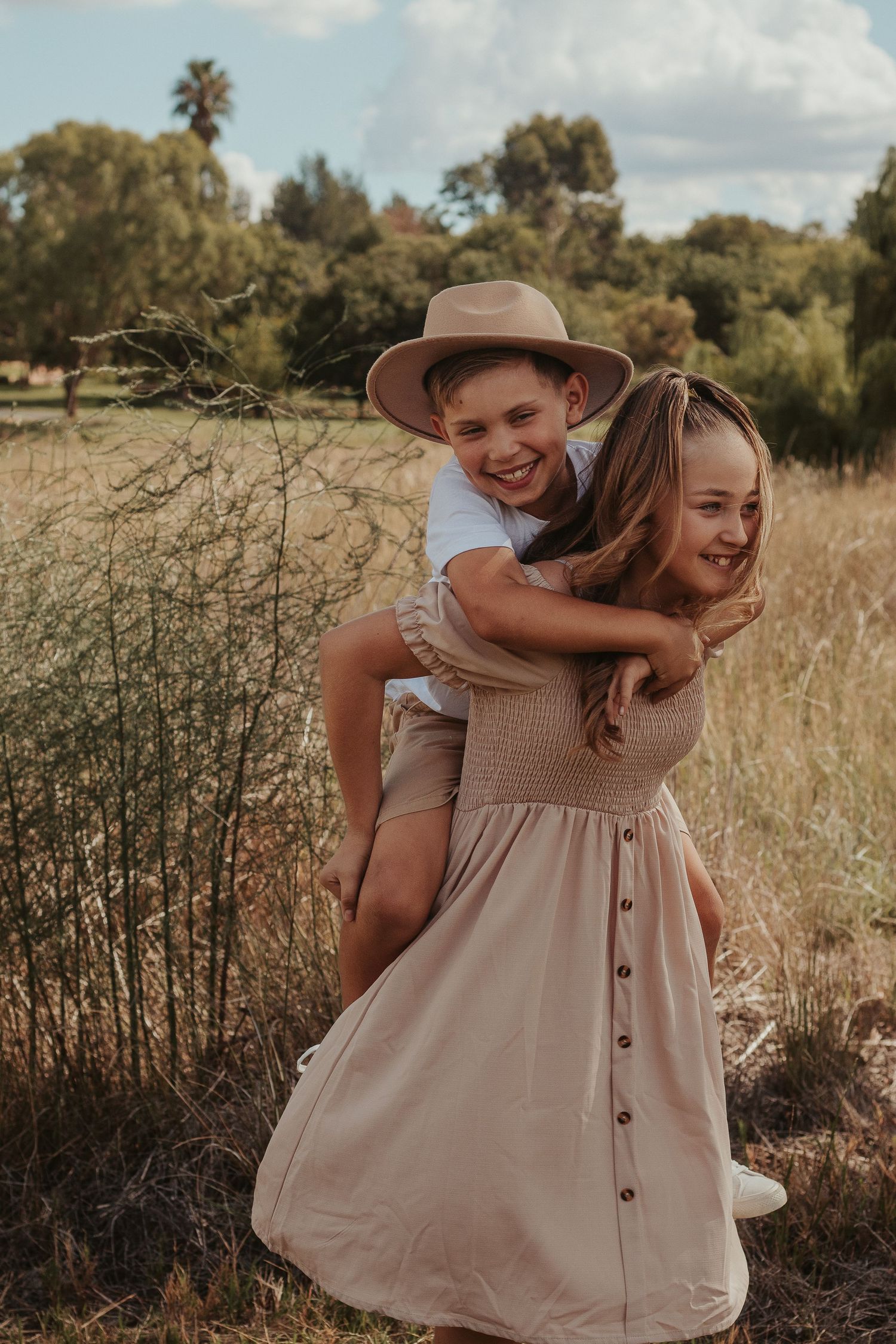 Playful moment captured in a field as siblings share a piggyback ride.