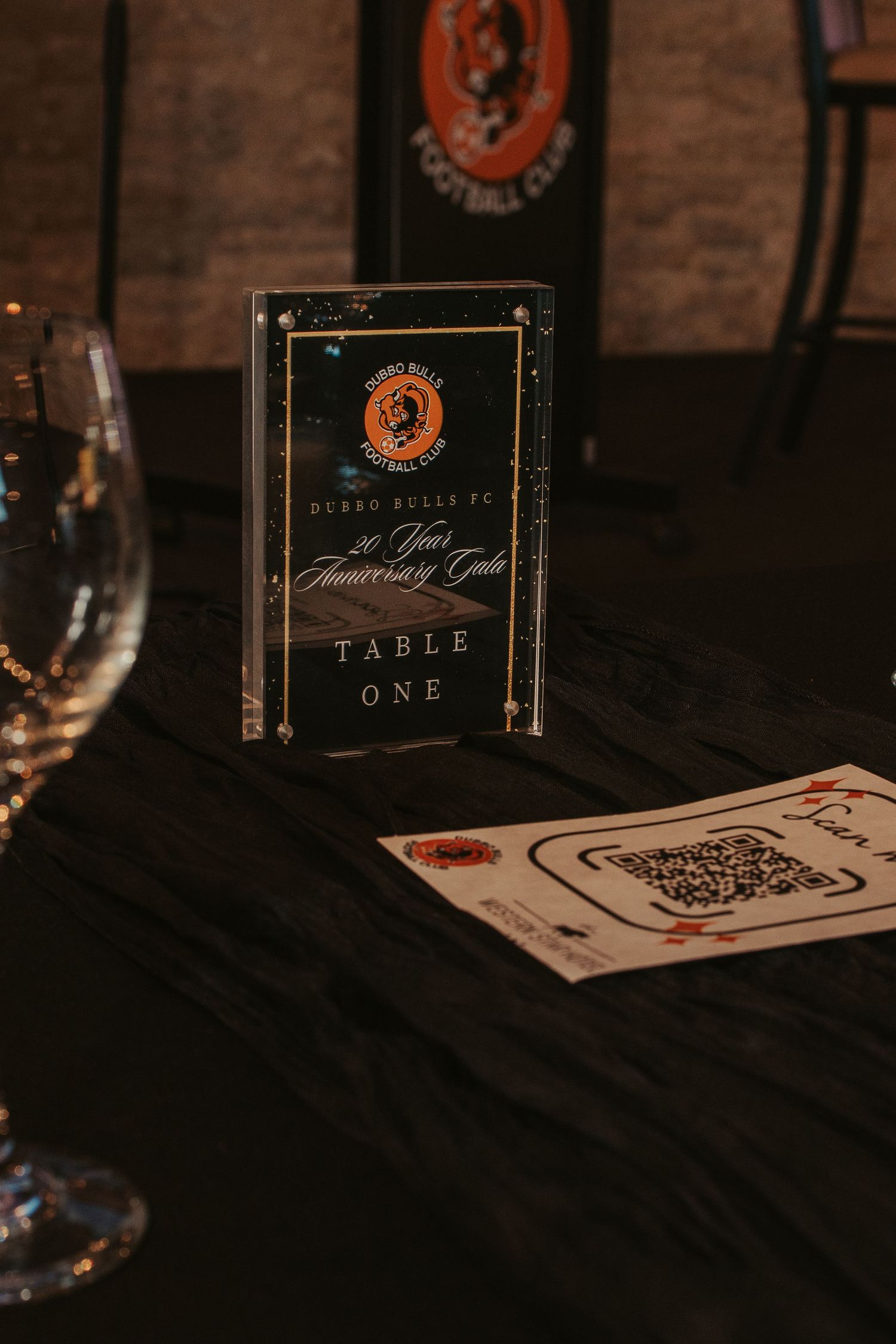 Table number one card displayed on dark tablecloth at formal event setting.