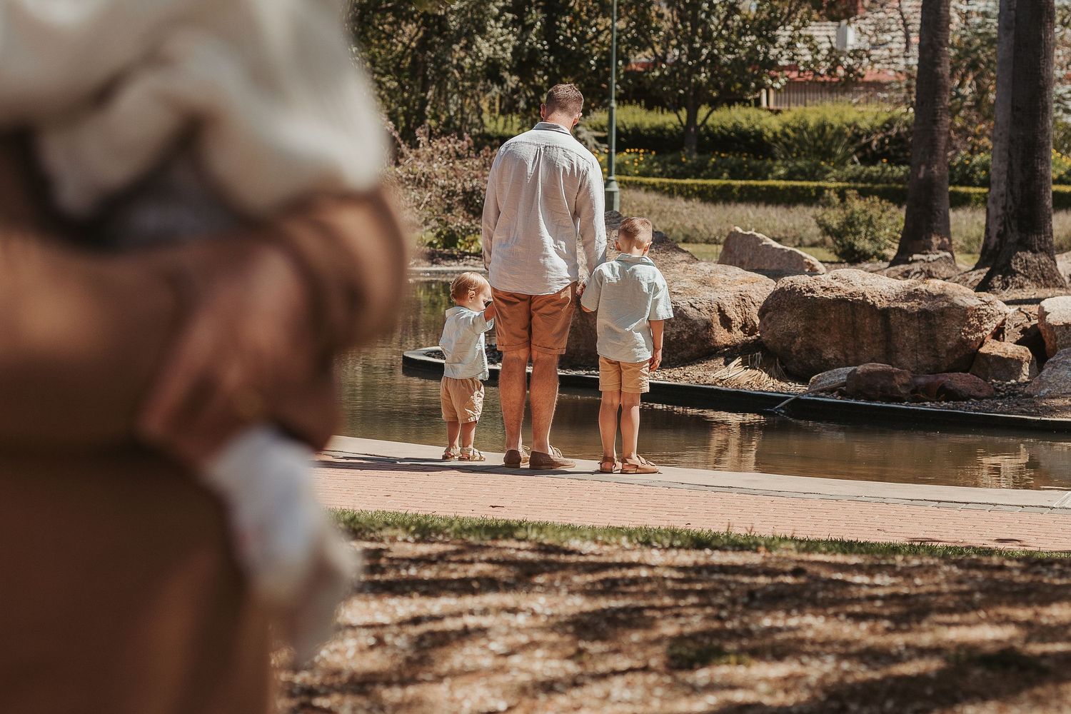 Outdoor family photography session in a natural park setting with dappled sunlight.