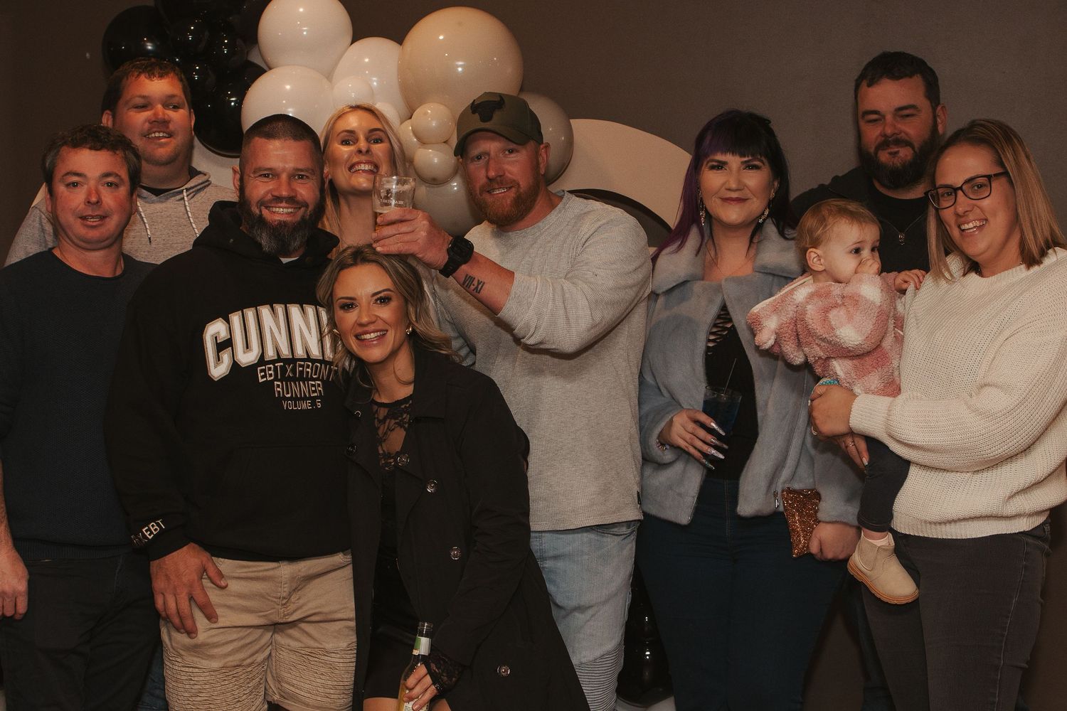 Large family group photo with baby at casual gathering.