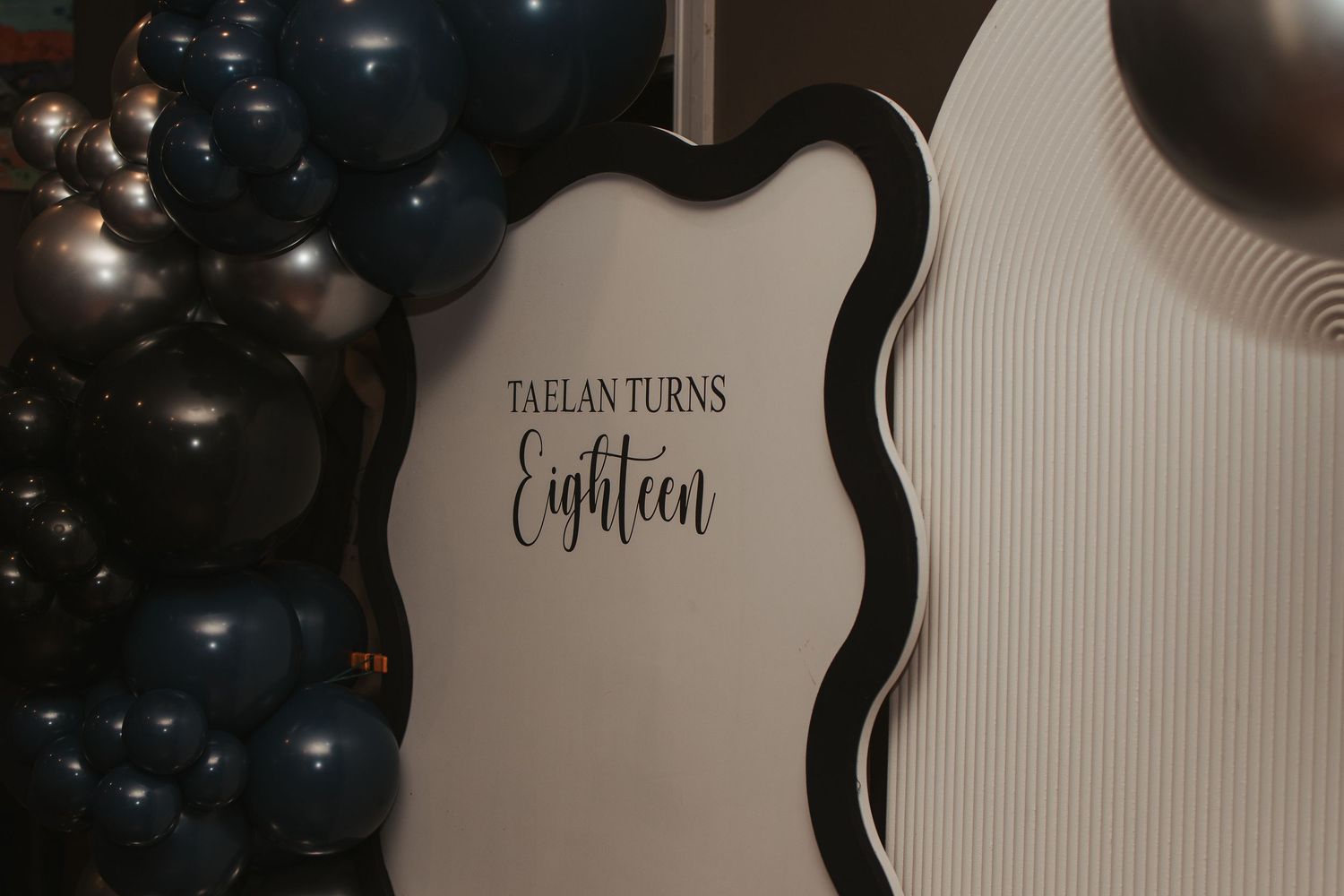 Dark balloons against a light wall with elegant text display.