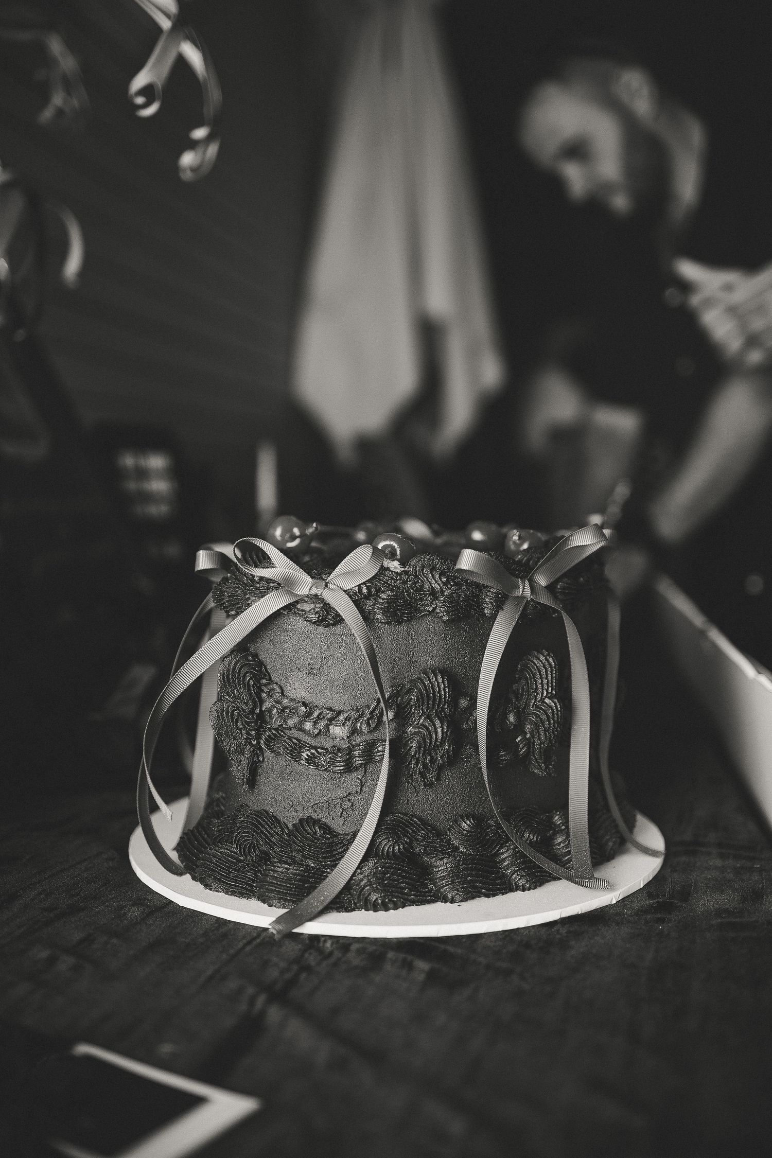 Black and white photo of elegant cake with delicate ribbon details.