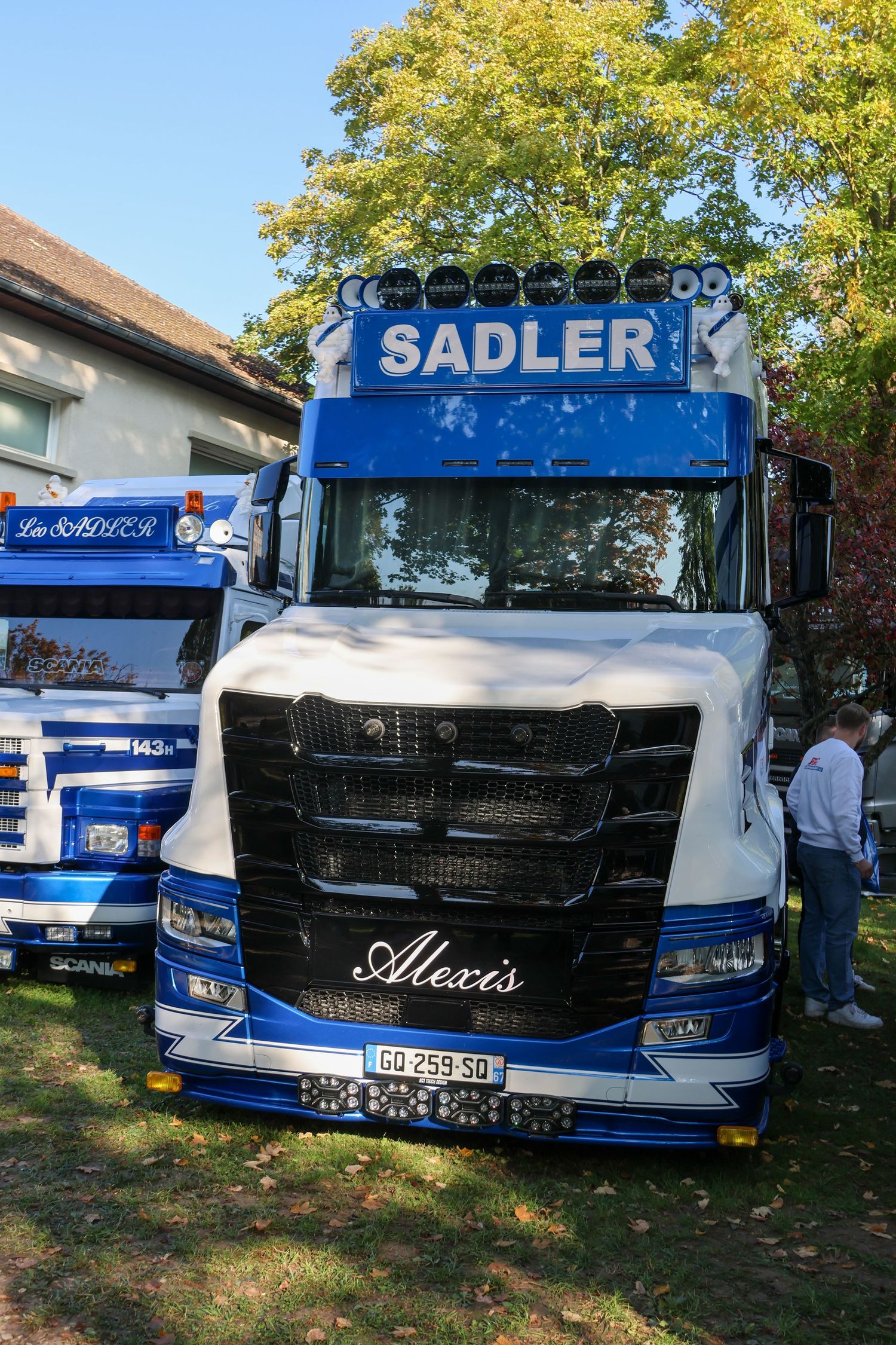 Blue and white Scania heavy truck with Sadler branding and personalized name Alexis on the grille.