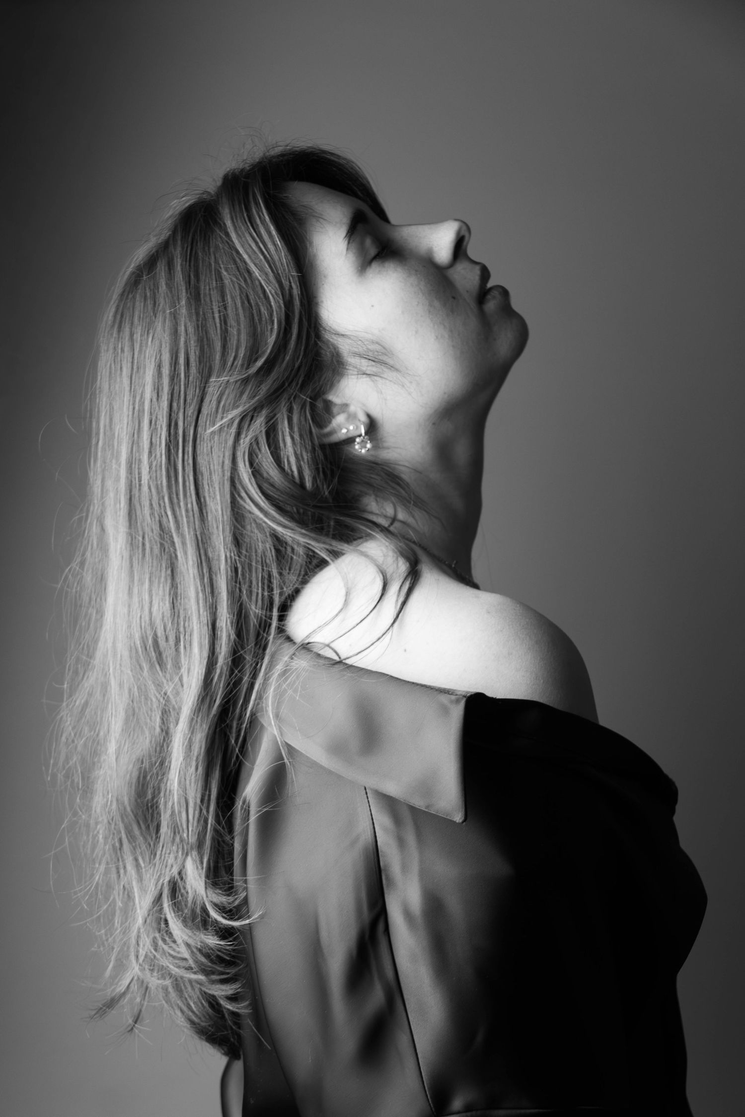Portrait en noir et blanc d'une femme aux cheveux longs renversant la tête en arrière avec grâce.