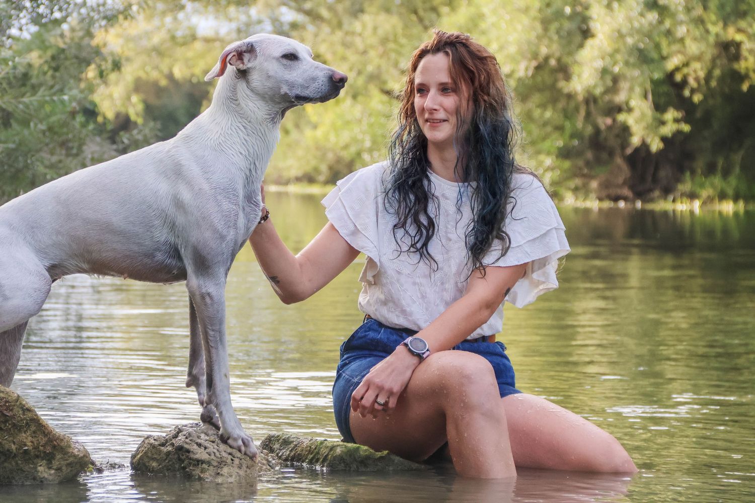 Séance animaux lifestyle — femme assise dans une rivière avec son chien blanc à ses côtés, photographe animaux Rethel Ardennes.