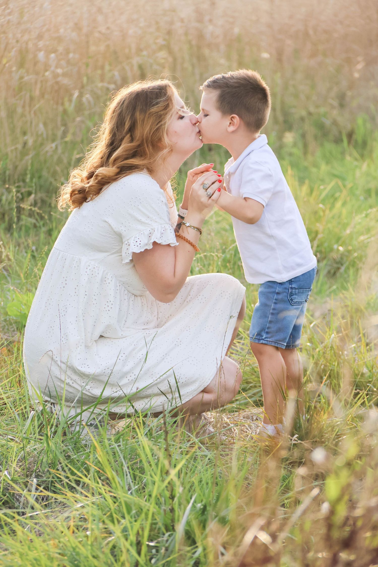 Séance famille — maman en robe blanche embrassant son fils en jean dans un champ, photographe famille Aisne Guignicourt.