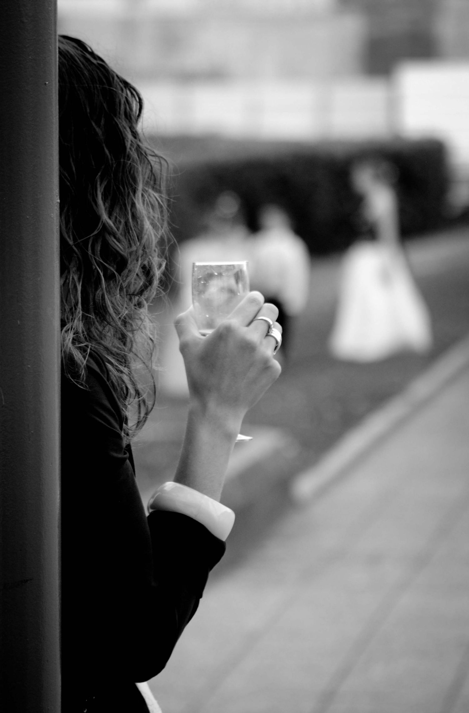 Black and white photo of a person with curly hair photographing a bride in the background.