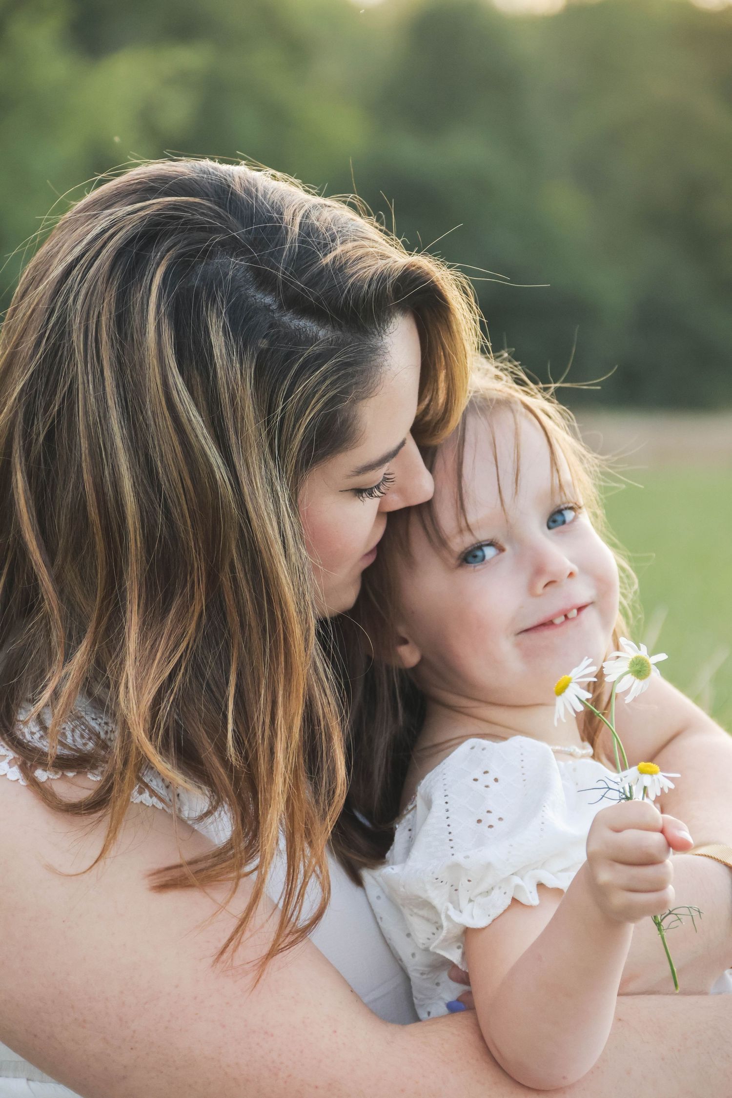 Séance famille lifestyle — maman nez à nez avec sa fille souriante tenant des marguerites blanches, photographe Châlons-en-Champagne Marne.