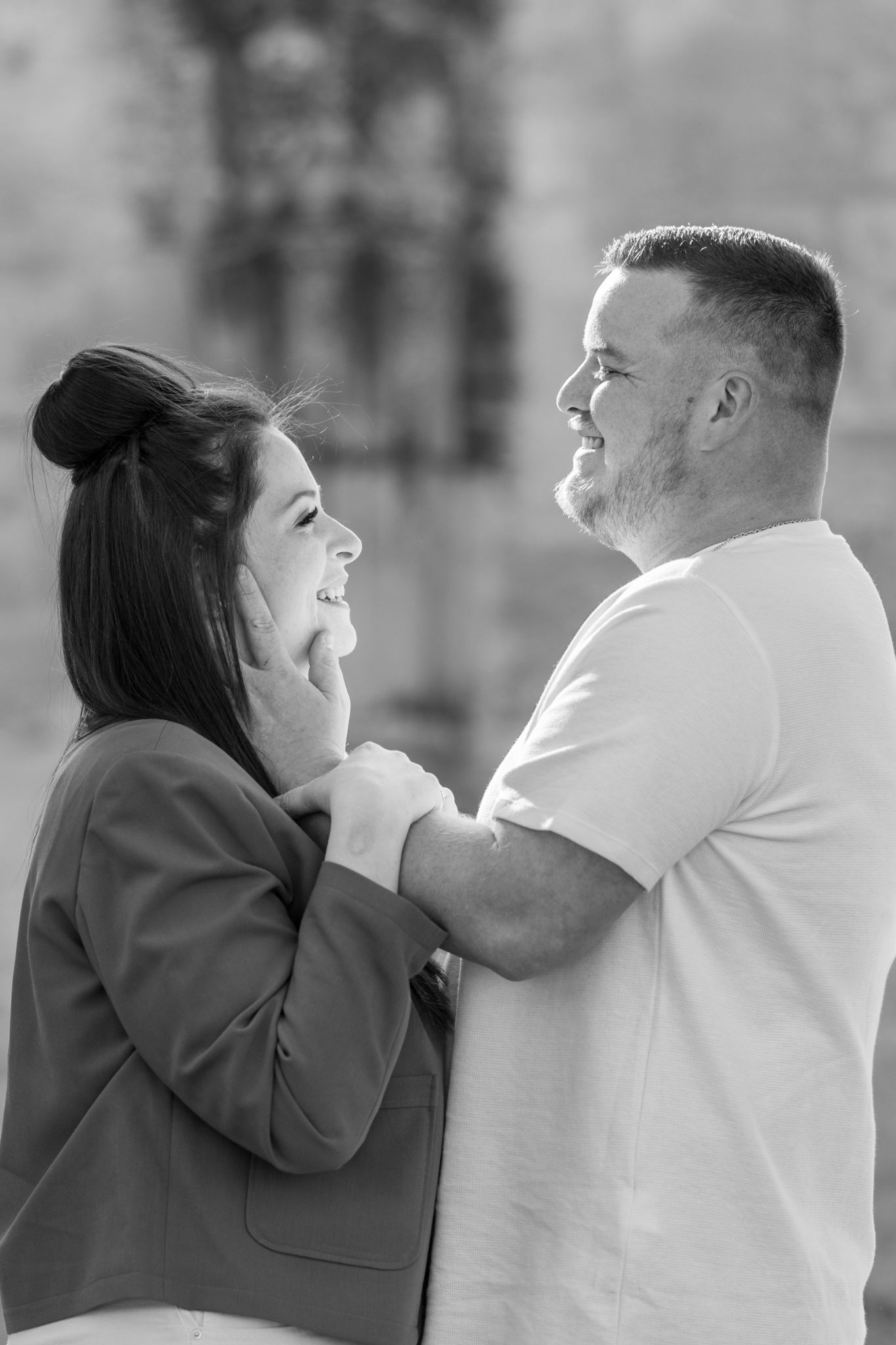 Black and white photo of a happy couple smiling and holding each other outdoors.