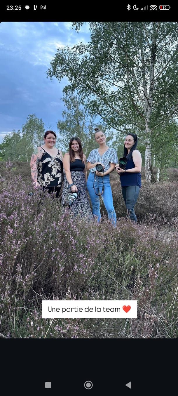 Four women photographers posing together in blooming heather field at dusk.