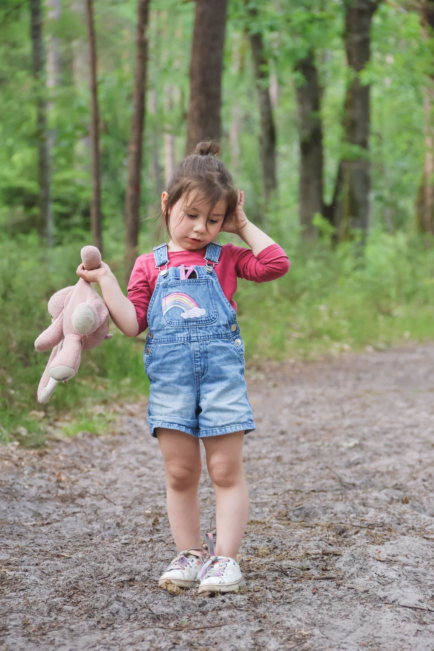 Séance famille lifestyle — petite fille en salopette jean tenant un lapin rose sur un chemin forestier, photographe Charleville-Mézières