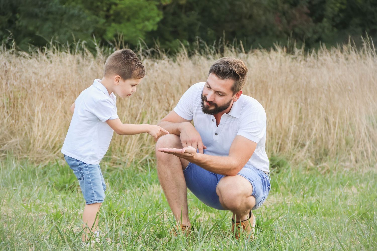Séance famille lifestyle — papa barbu complice avec son petit garçon près d'un champ de blé, photographe Aisne Guignicourt.