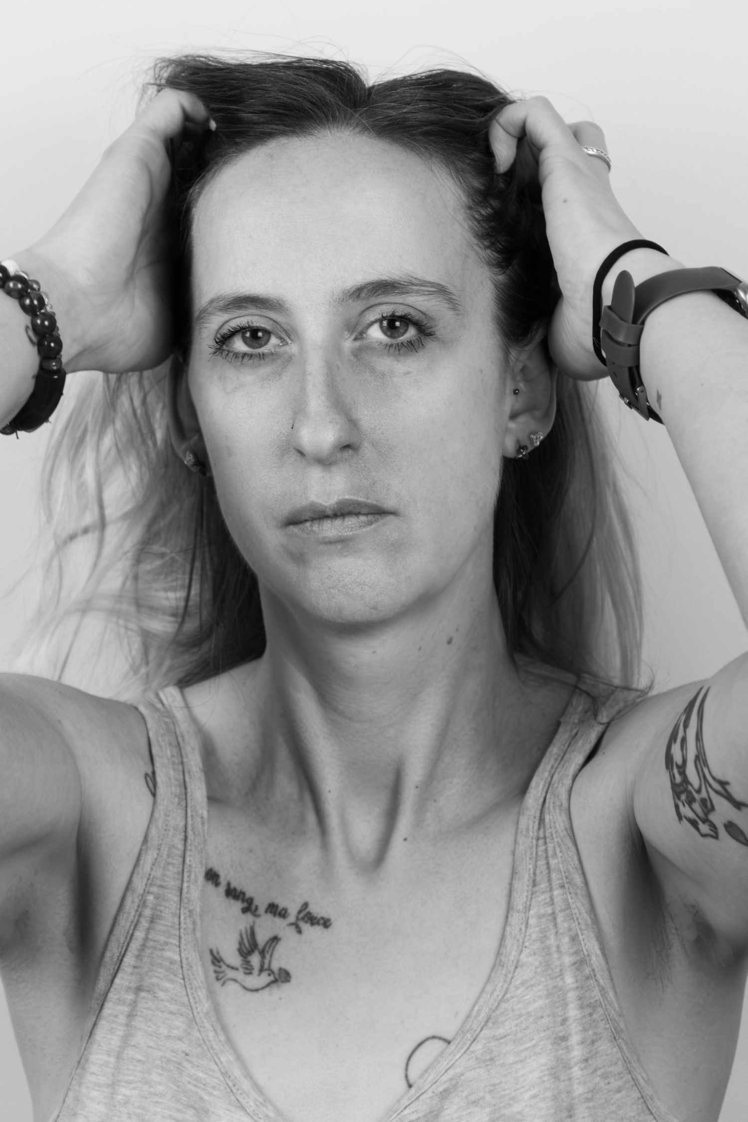 Séance Harmonie — portrait studio noir et blanc femme tatouée relevant ses cheveux regard caméra, photographe Châlons-en-Champagne Marne.