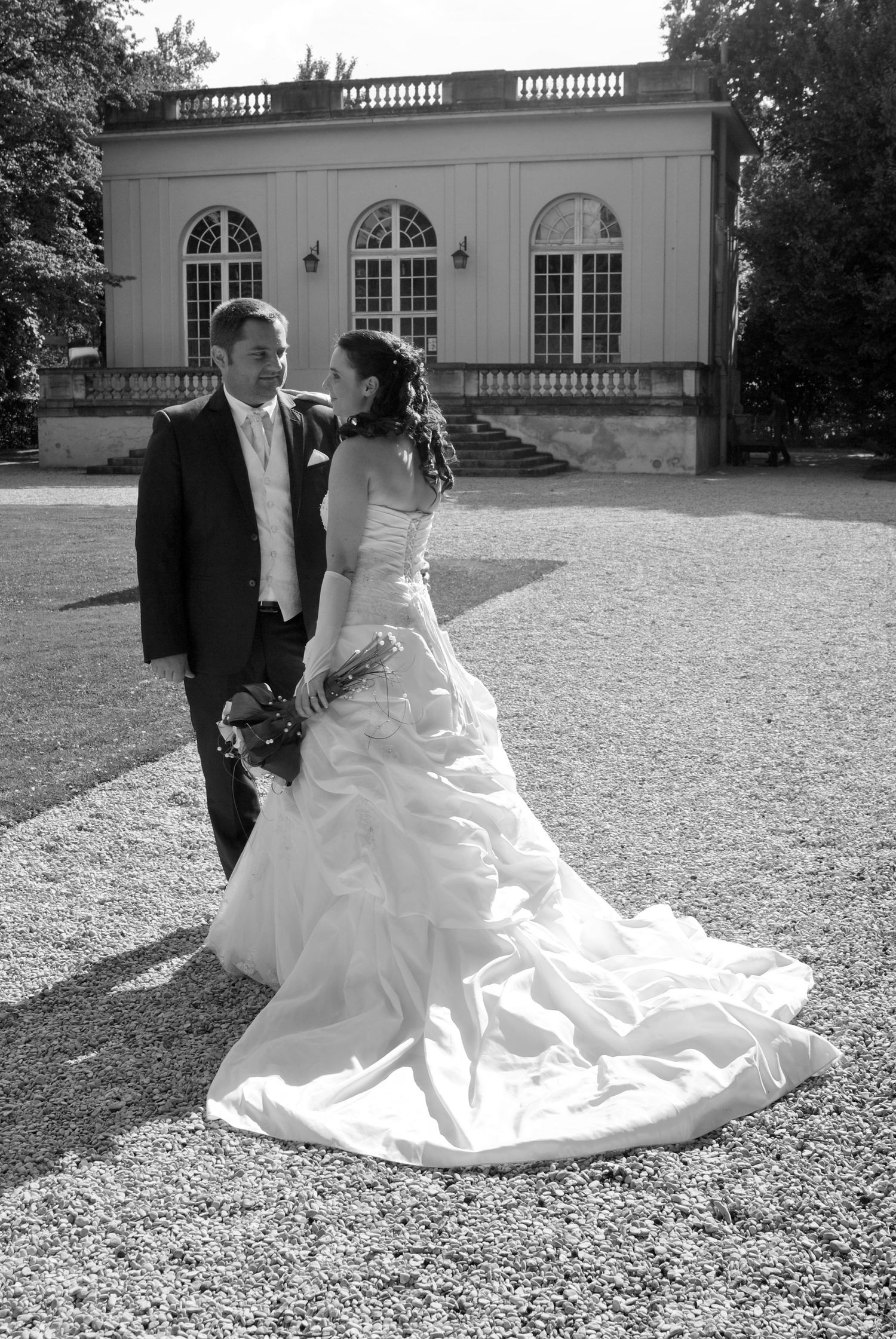Bride and groom walk together in black and white photo near elegant building.